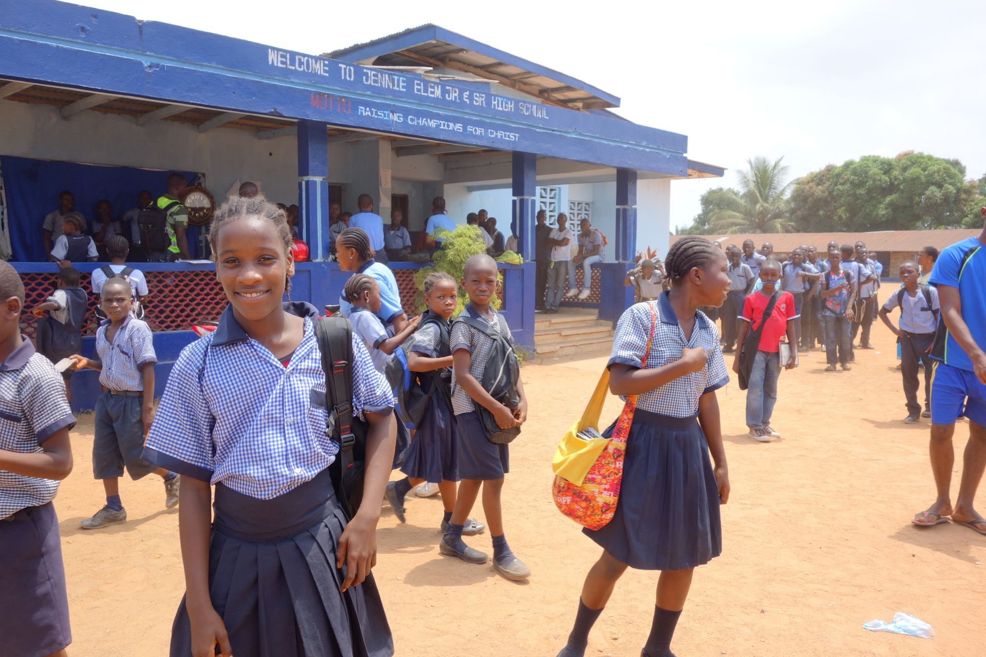 Schoolchildren in blue uniforms walking and smiling outside a school building