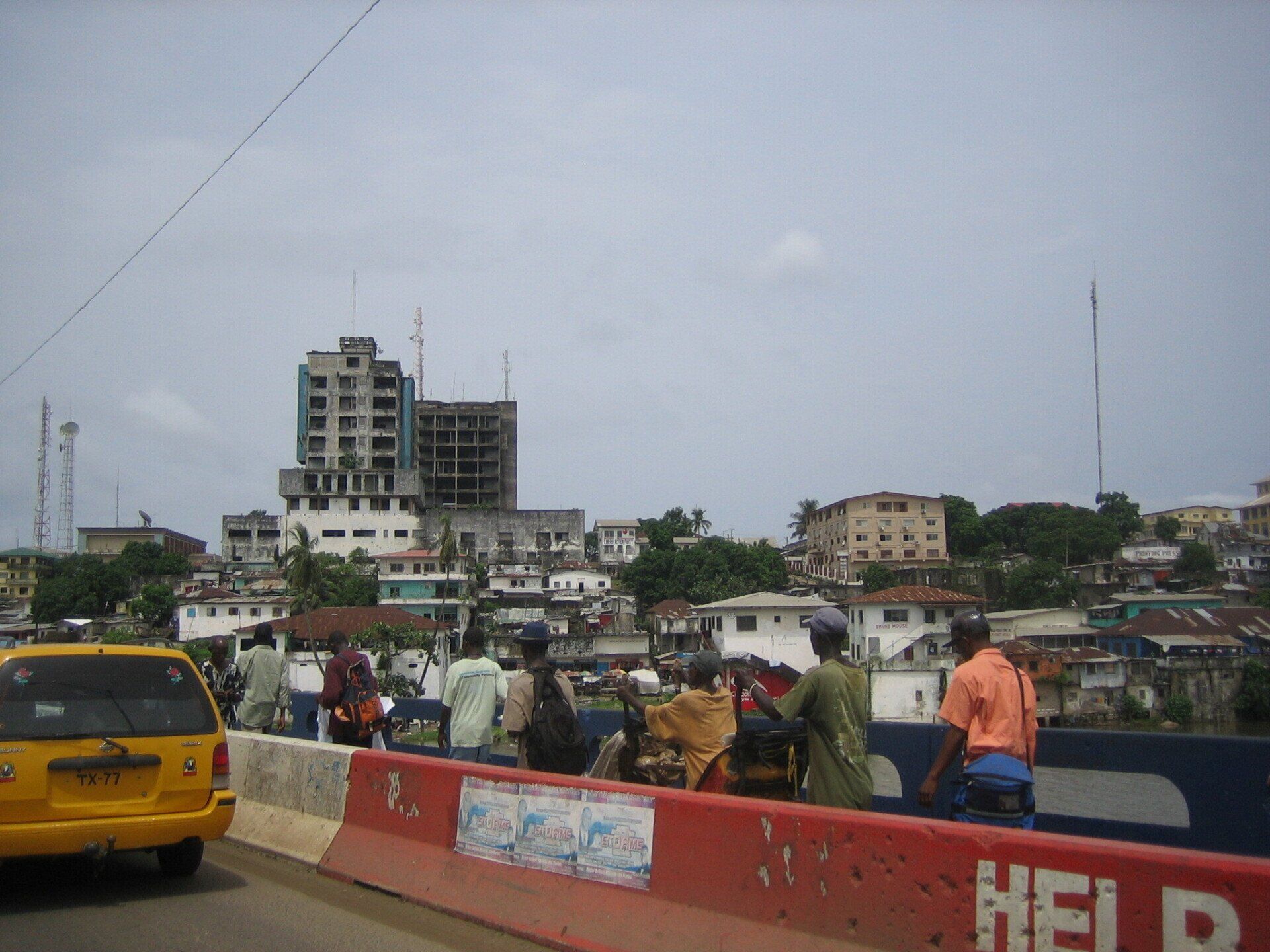 Busy city street with pedestrians, yellow taxi, and buildings under a hazy sky