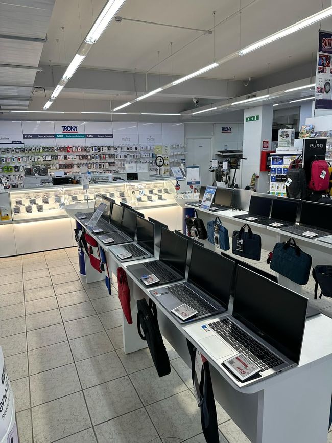 Una fila di computer portatili sono appoggiati sui tavoli di un negozio.