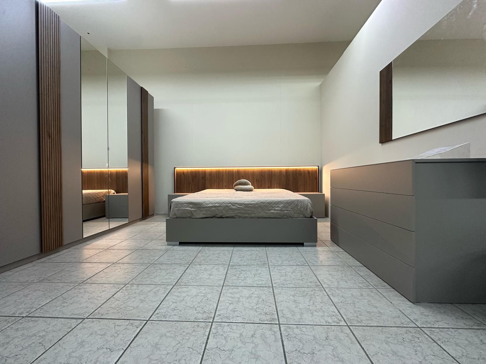 Una camera da letto con letto, cassettiera, specchio e armadio.