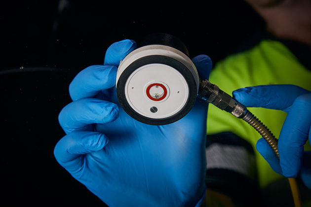 A Man Holding A Windscreen Crack Repair Tool — Simmons Glass & Trim In Bathurst, NSW