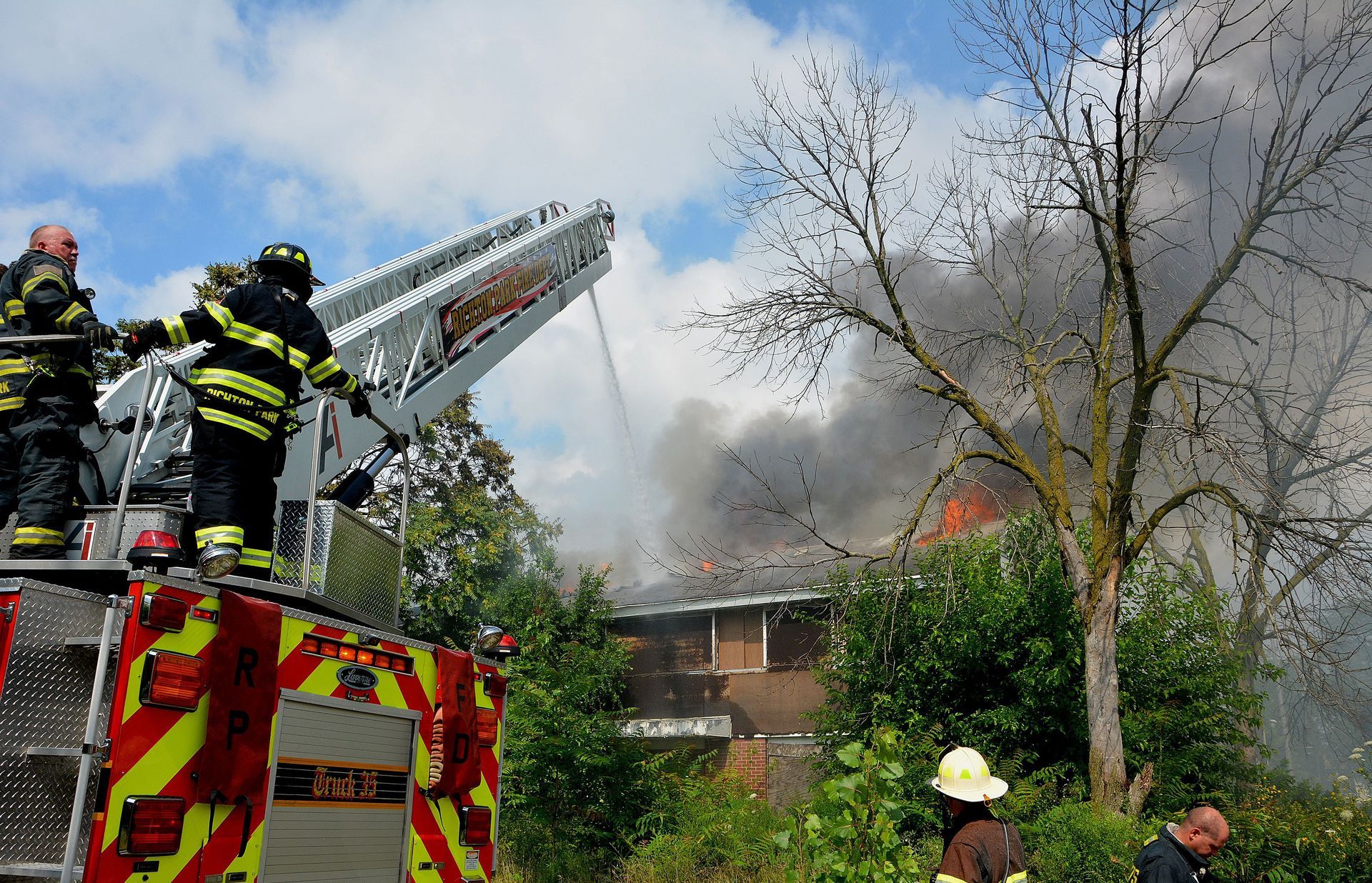 Firefighters on a ladder truck working a house fire, showing the fire peril covered by Arizona home insurance