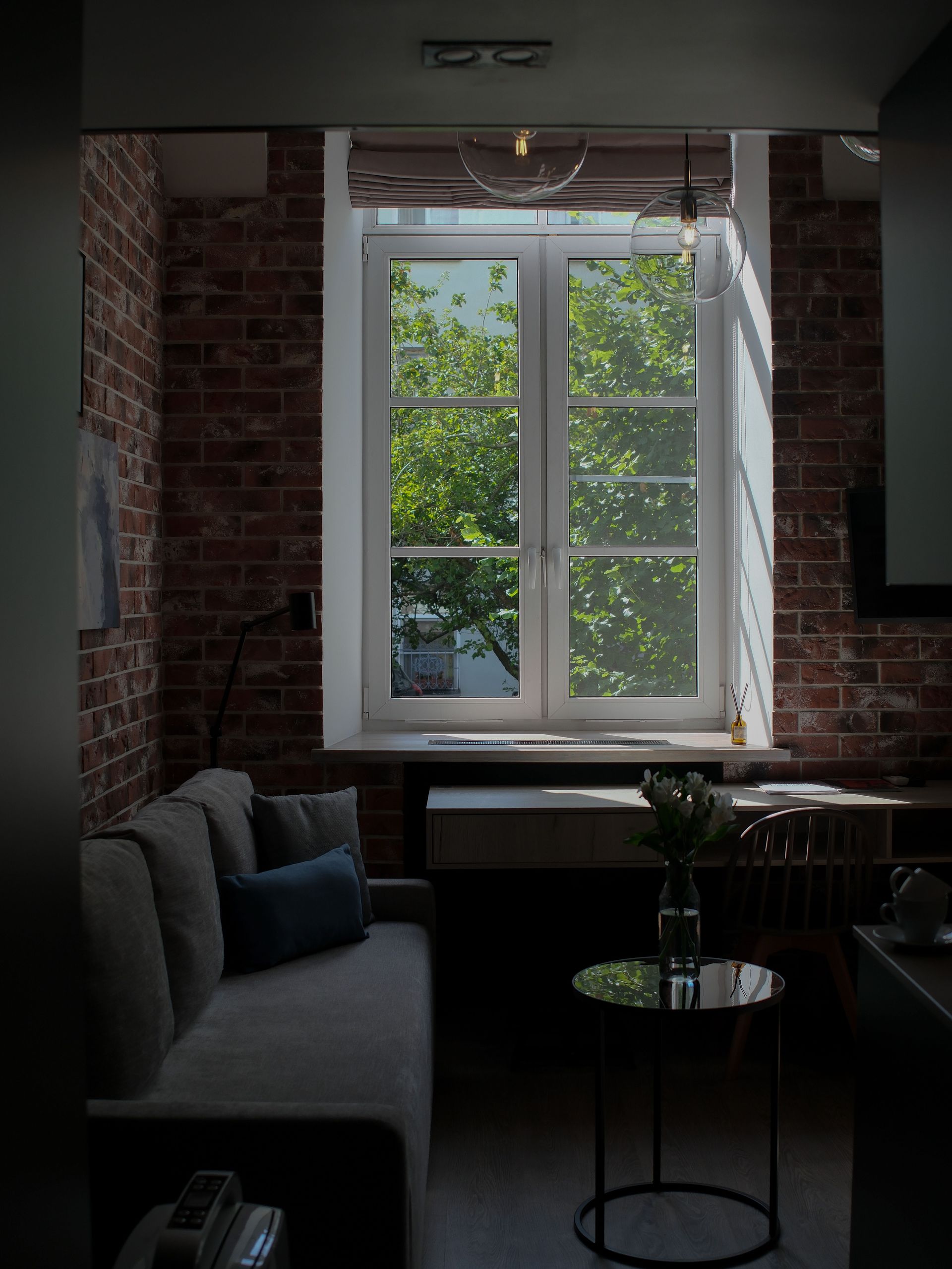 Bright apartment living room with couch and window, showing belongings renters insurance covers in Arizona