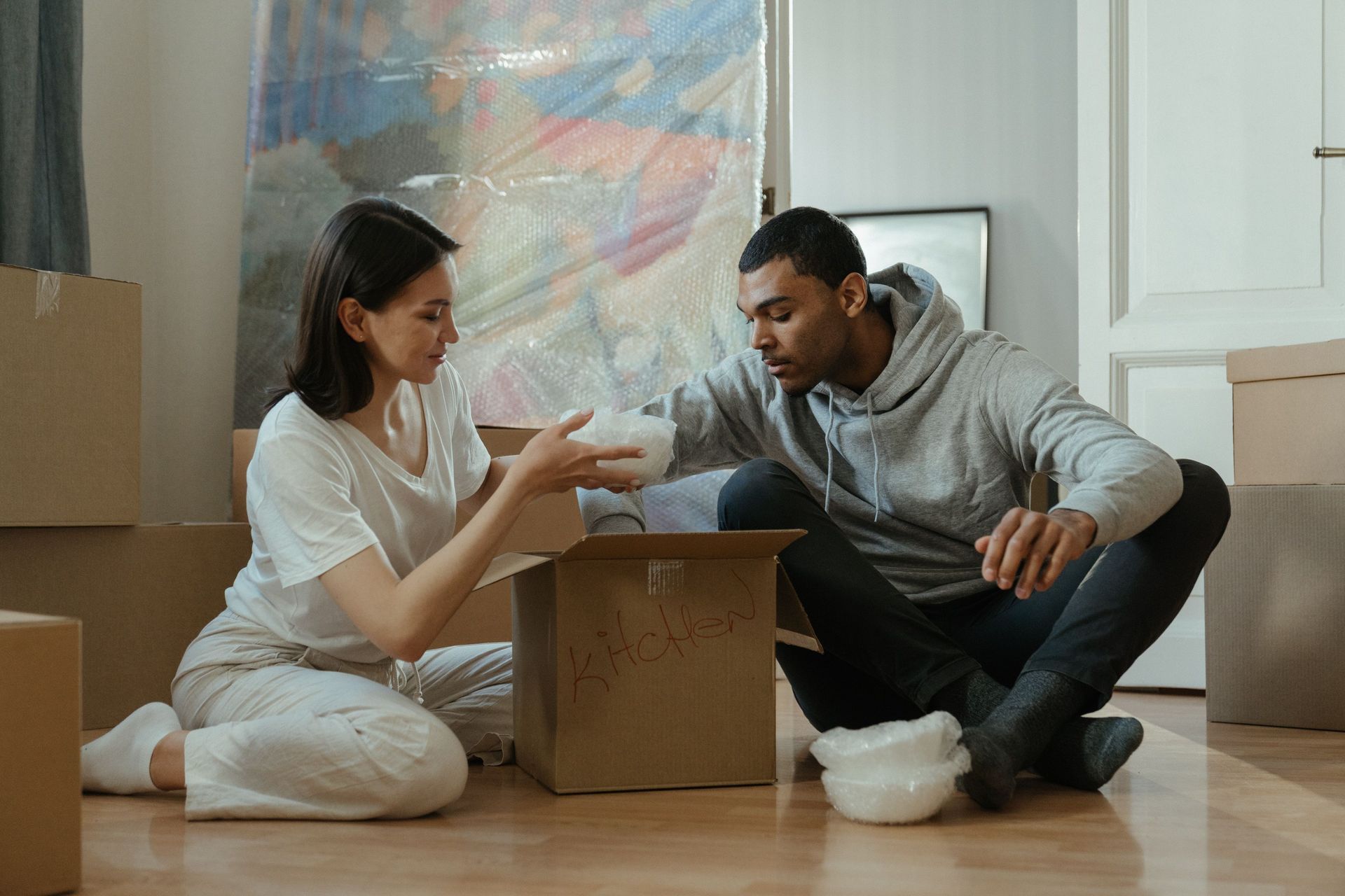 Young couple unpacking moving boxes in the living room of their newly purchased first home in Arizona