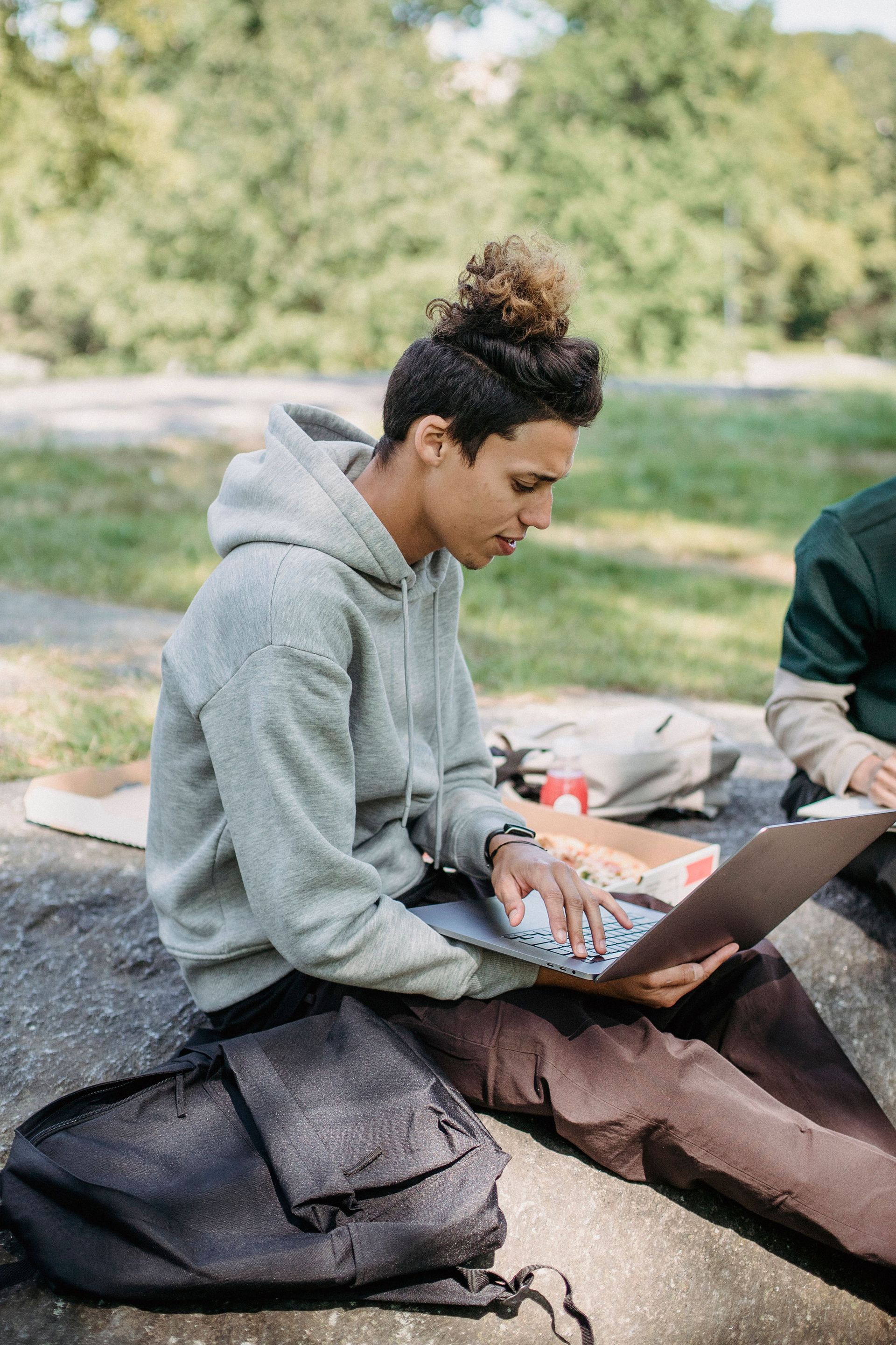 Arizona college student studying on a laptop outdoors, keeping the grades that earn a good student auto insurance discount