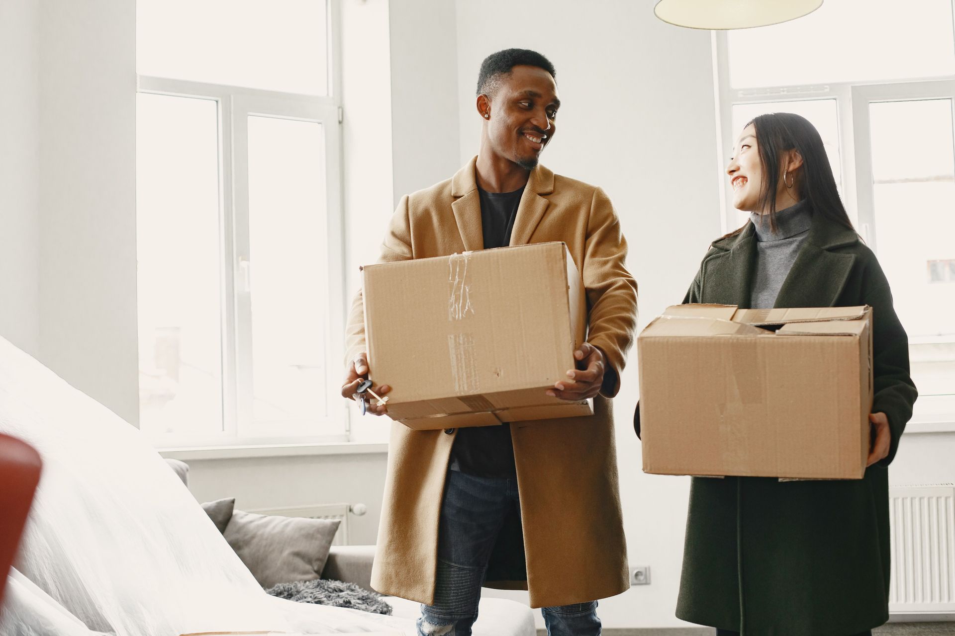 Couple carrying moving boxes into a new Arizona apartment, the moment to set up renters insurance