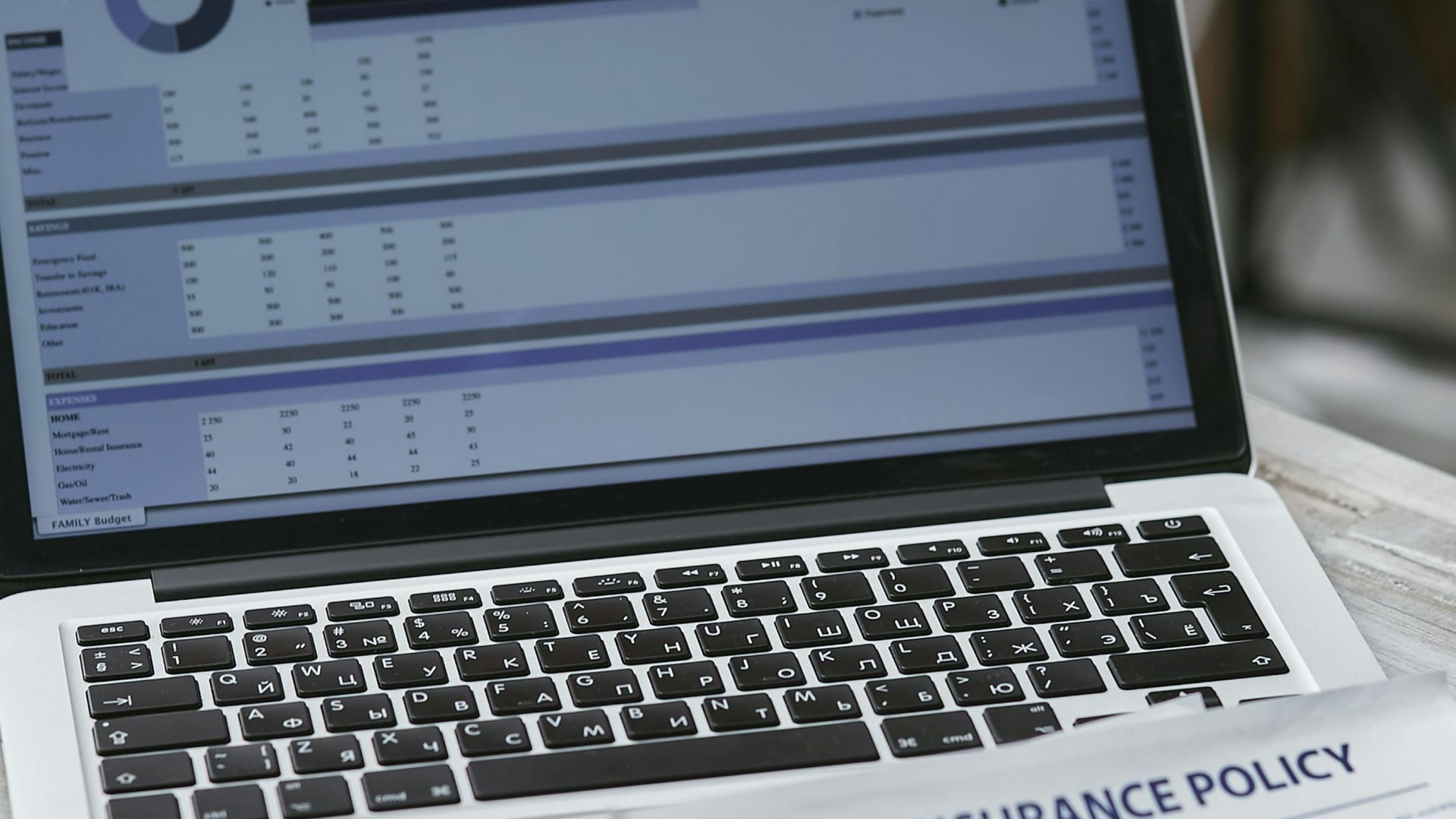 Laptop displaying a spreadsheet, with an insurance policy document below.