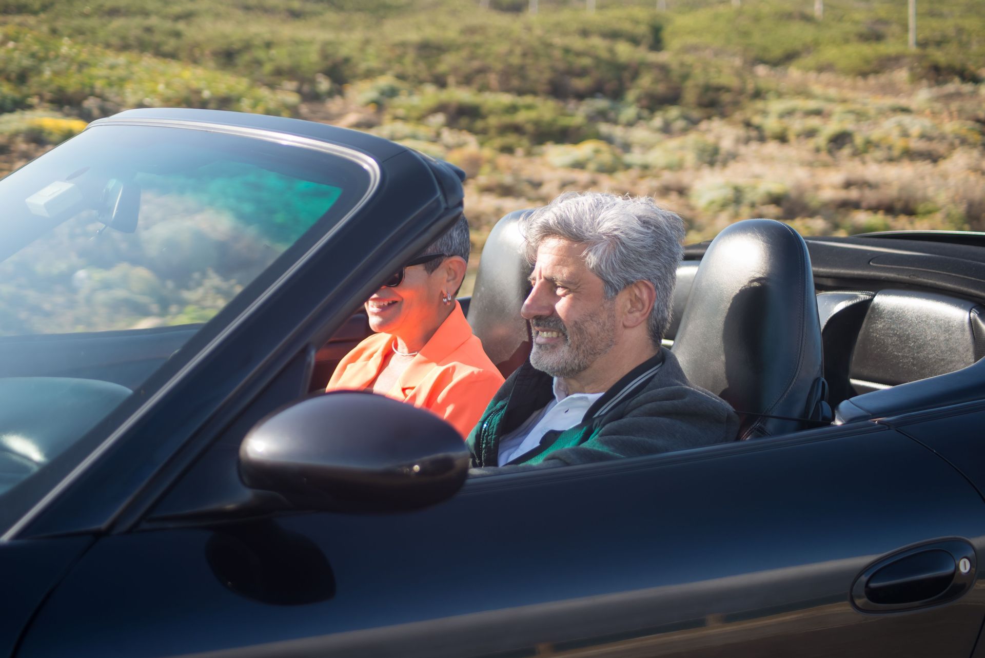 Retired couple driving a convertible on a sunny desert road near Surprise, AZ, a reminder to review car insurance