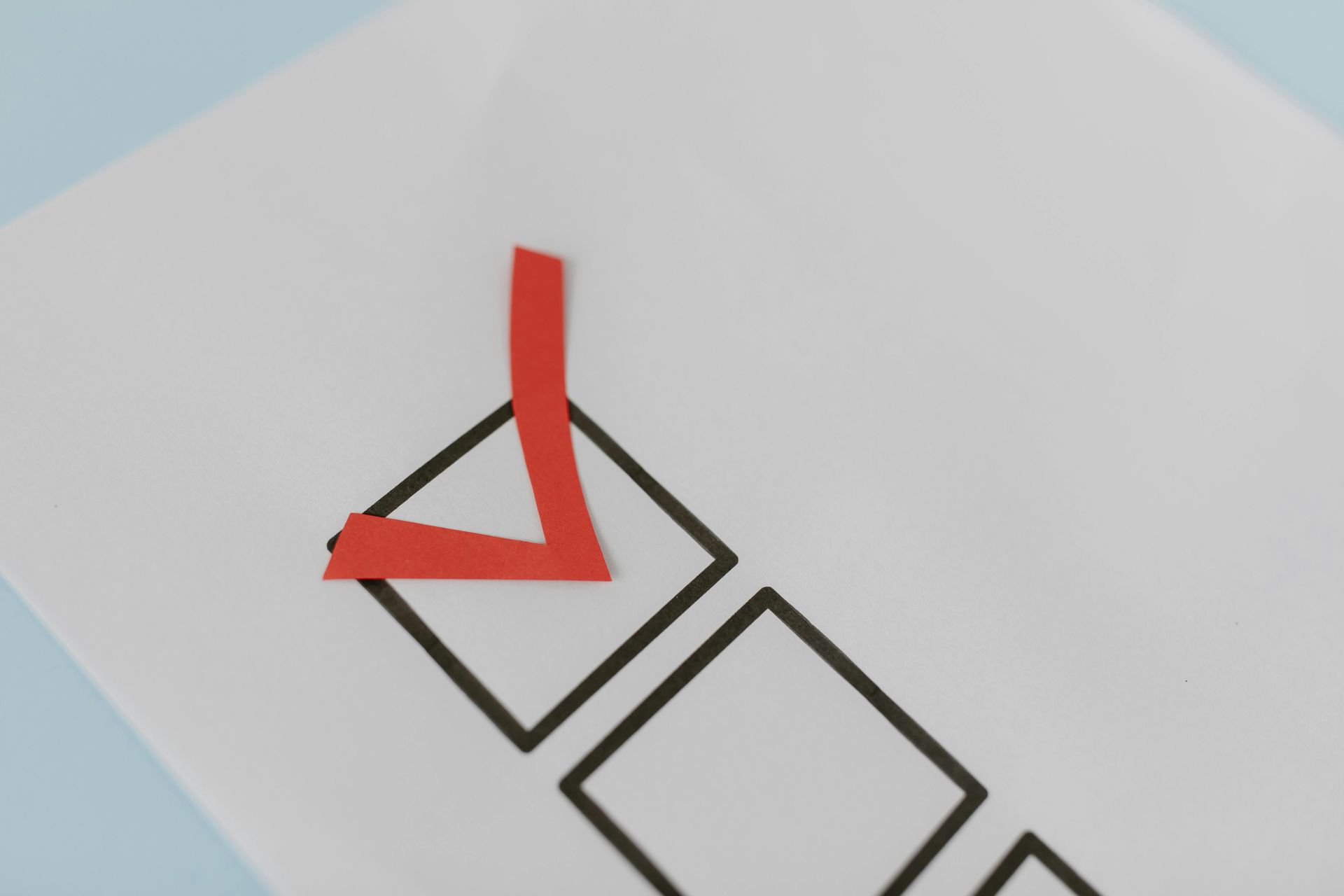 A red checkmark is placed inside the first of several empty black outlined square boxes on a white surface.