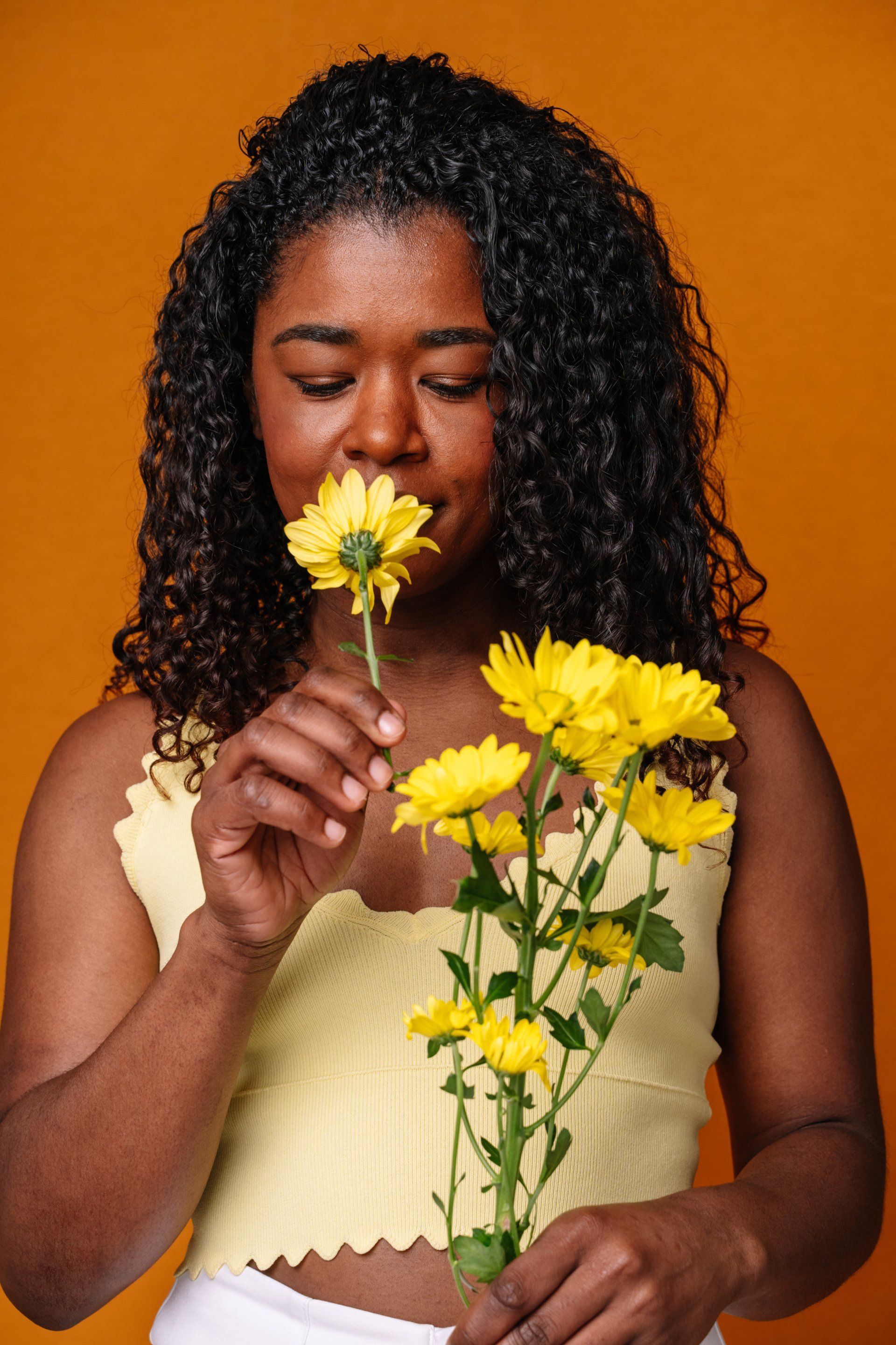 Uma mulher está cheirando um buquê de flores amarelas.