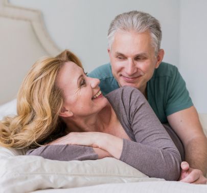 Um homem e uma mulher estão deitados em uma cama e sorrindo