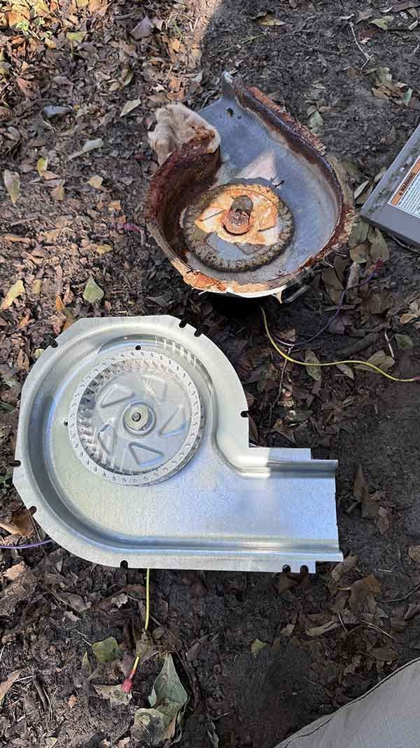 Two broken metal parts on dirt and leaves, one rusted and one silver.