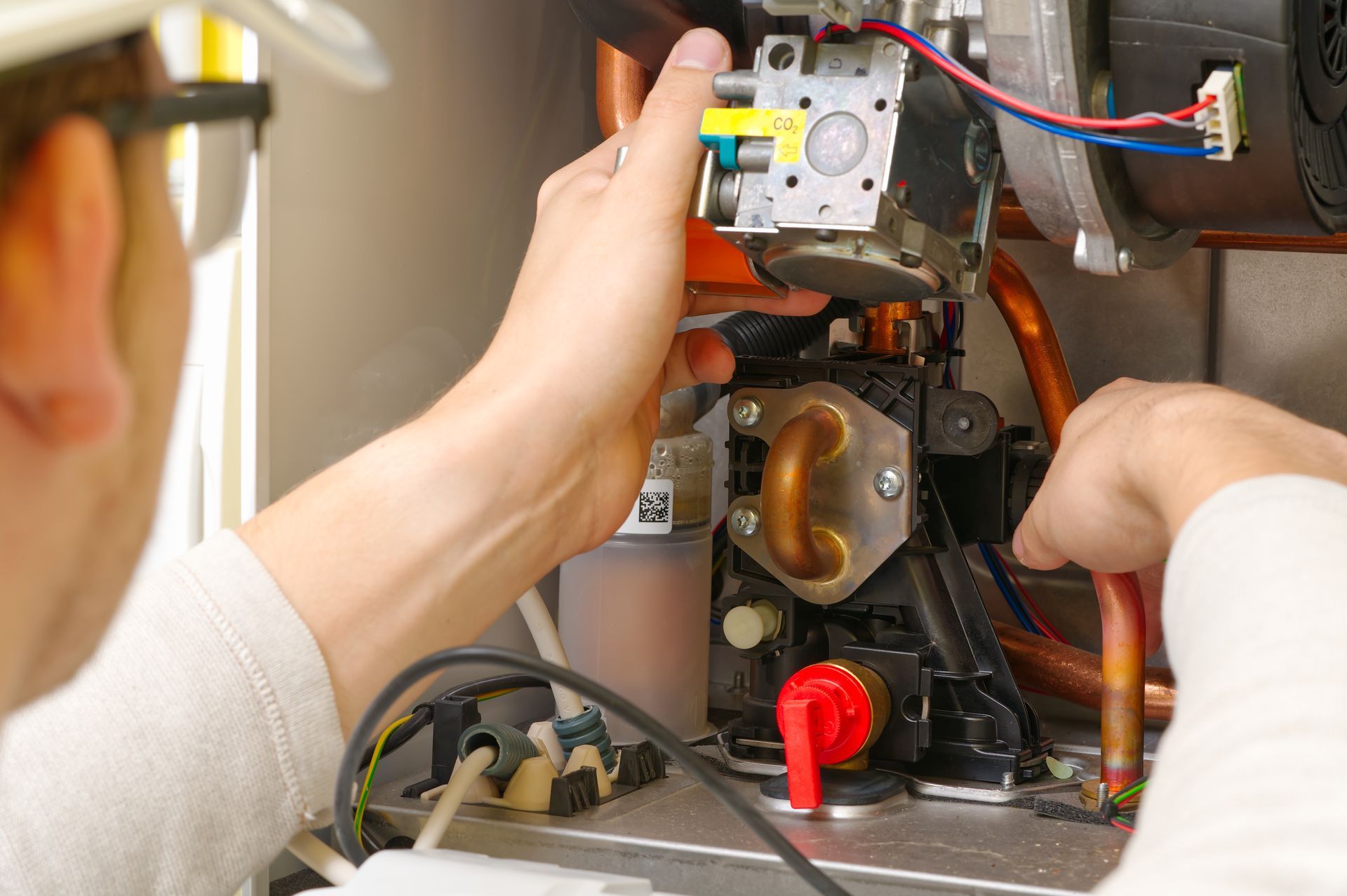 Technician repairing the inside of a machine with exposed wiring and metal components.