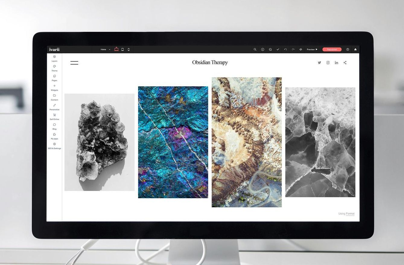 Computer monitor displaying four abstract artwork panels in black, blue, beige, and gray