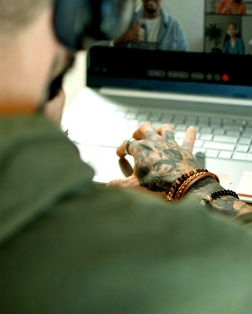 Person typing on a laptop during a video call, with two people visible on the screen.