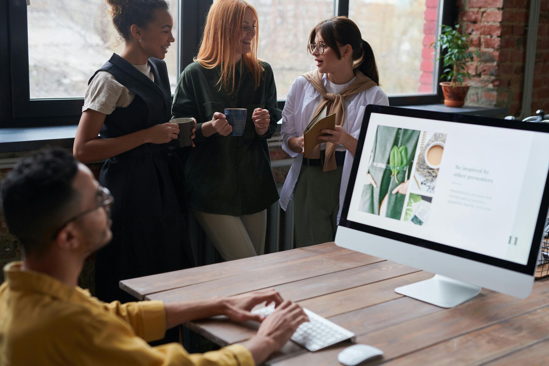 Team discussing a presentation on a large desktop monitor in a bright office meeting space