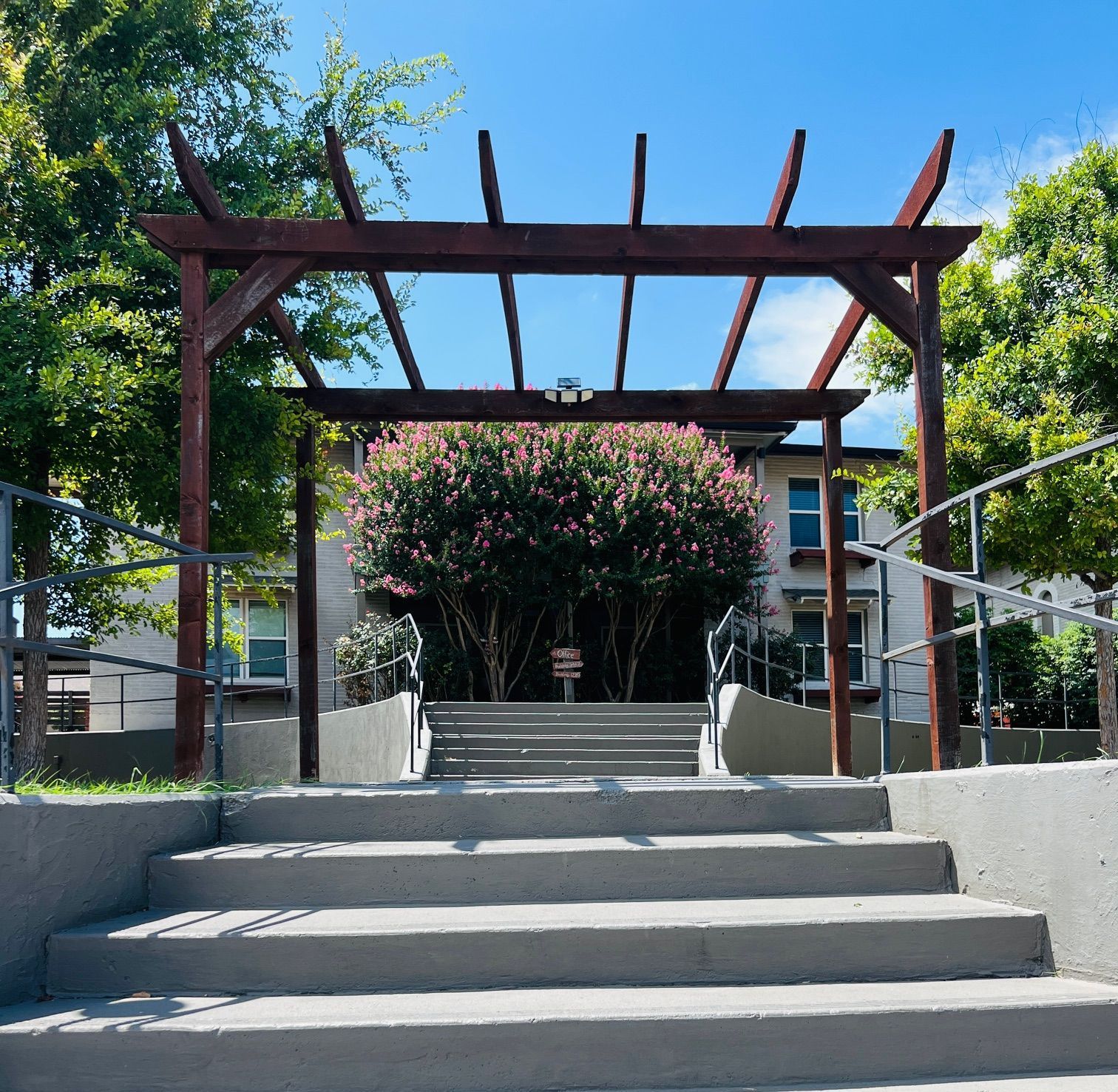 A wooden pergola over a set of stairs leading to a building
