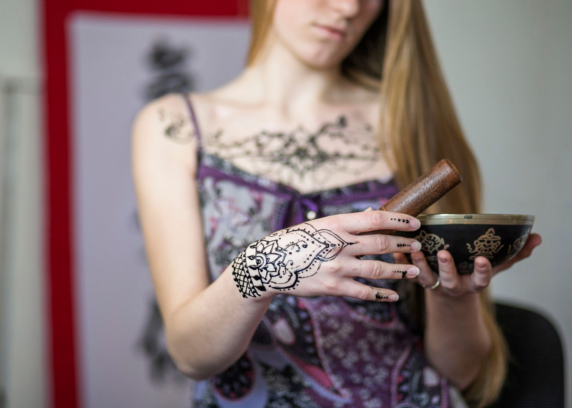 A woman with a henna tattoo on her hand is holding a bowl.