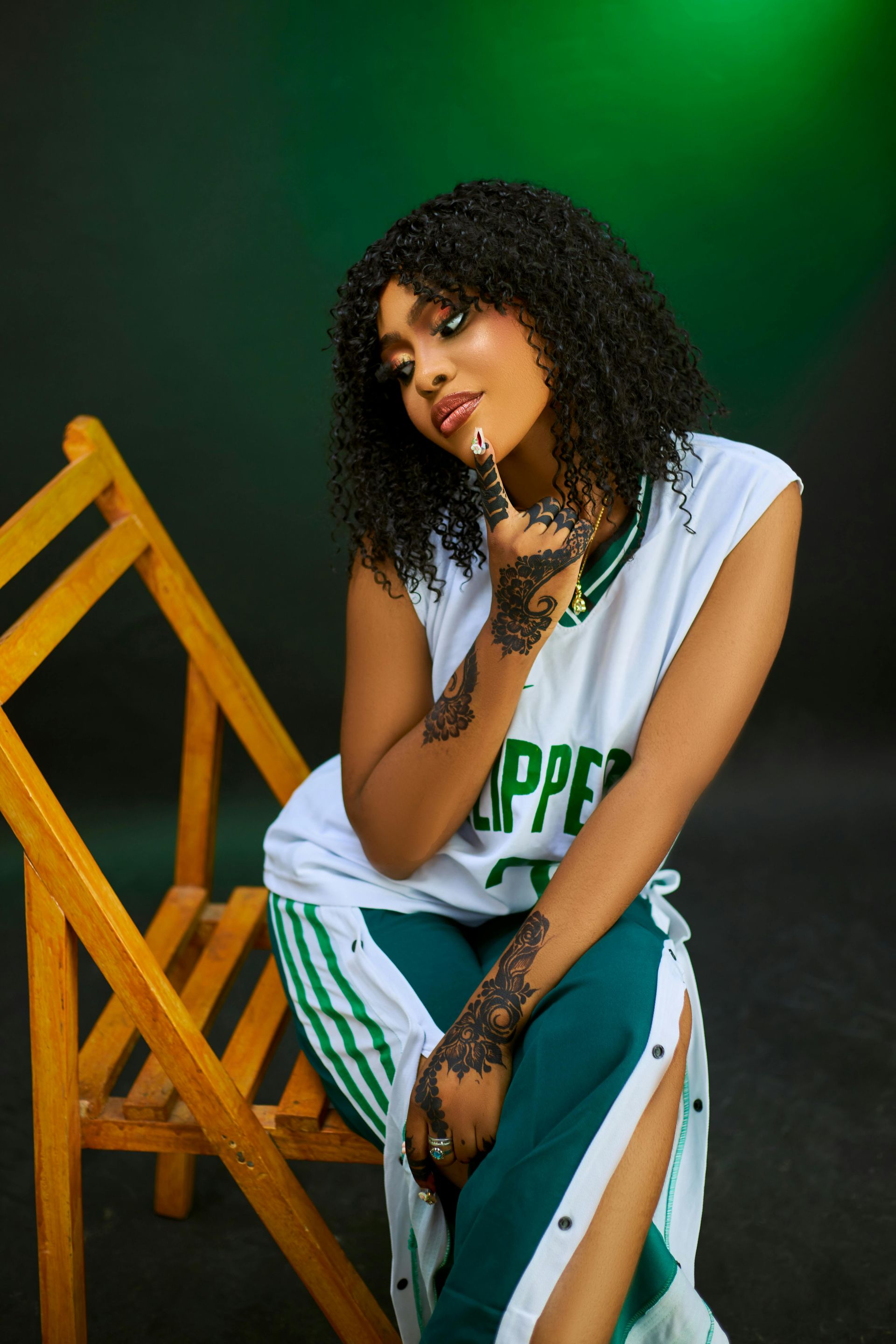 A woman in a basketball uniform is sitting on a wooden chair.