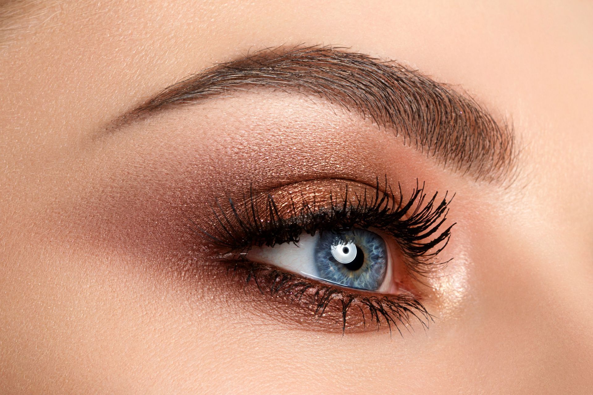 A close up of a woman 's blue eye with brown eyeshadow.