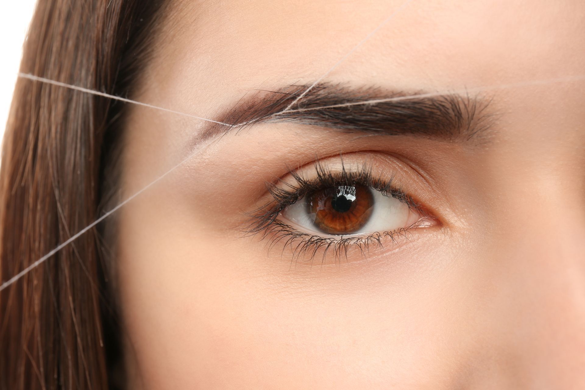 A woman is threading her eyebrows with a string.