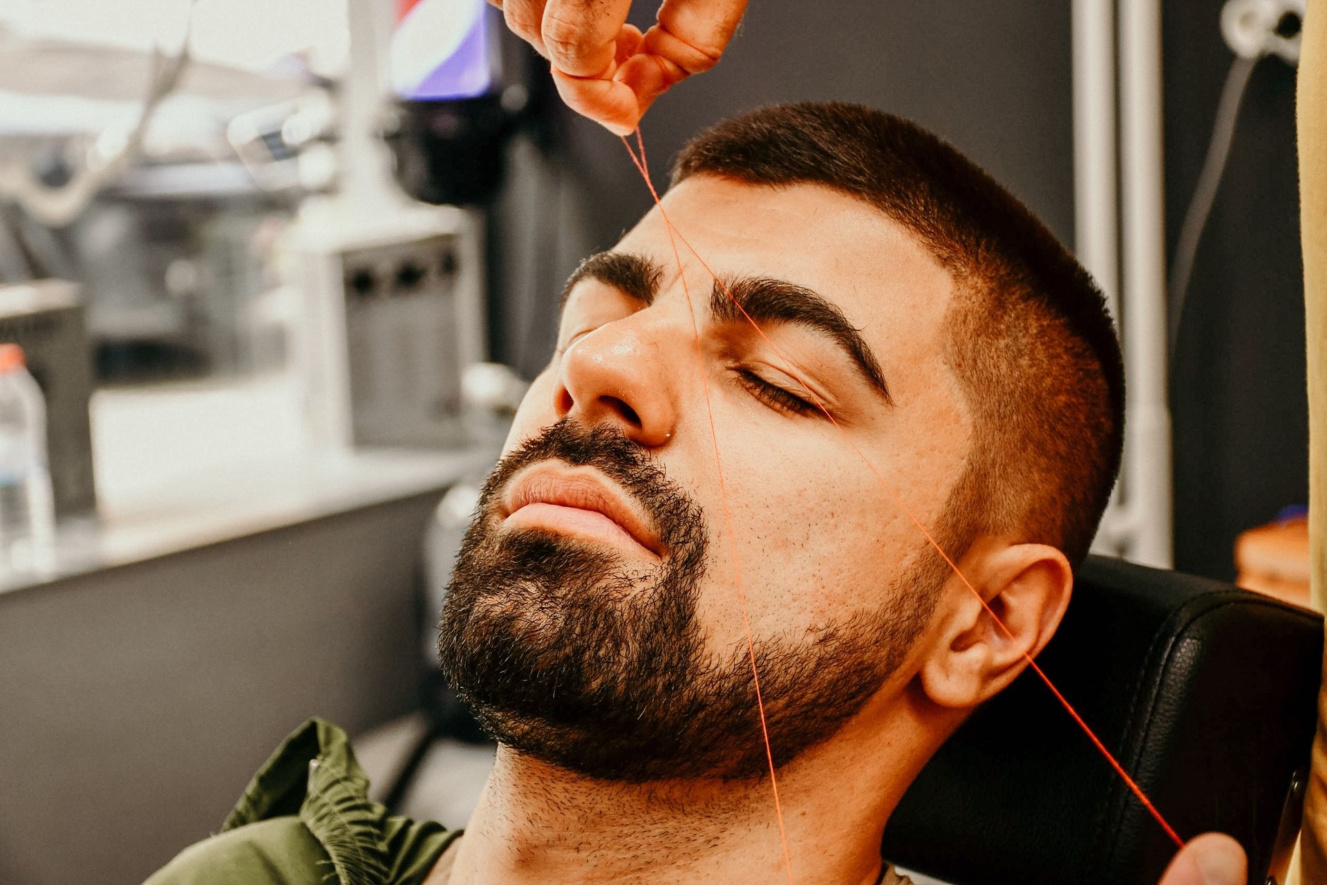 A man with a beard is getting his beard shaved by a barber.