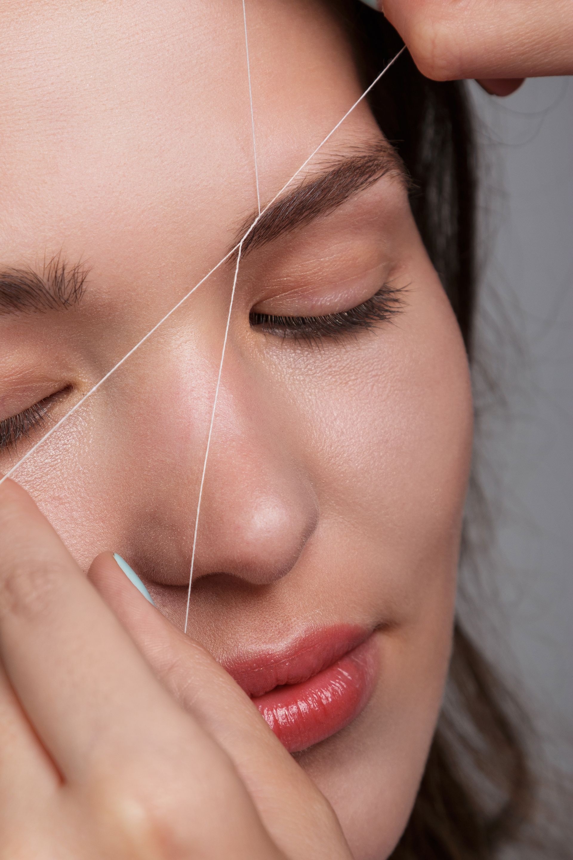 A close up of a woman getting her eyebrows threaded.
