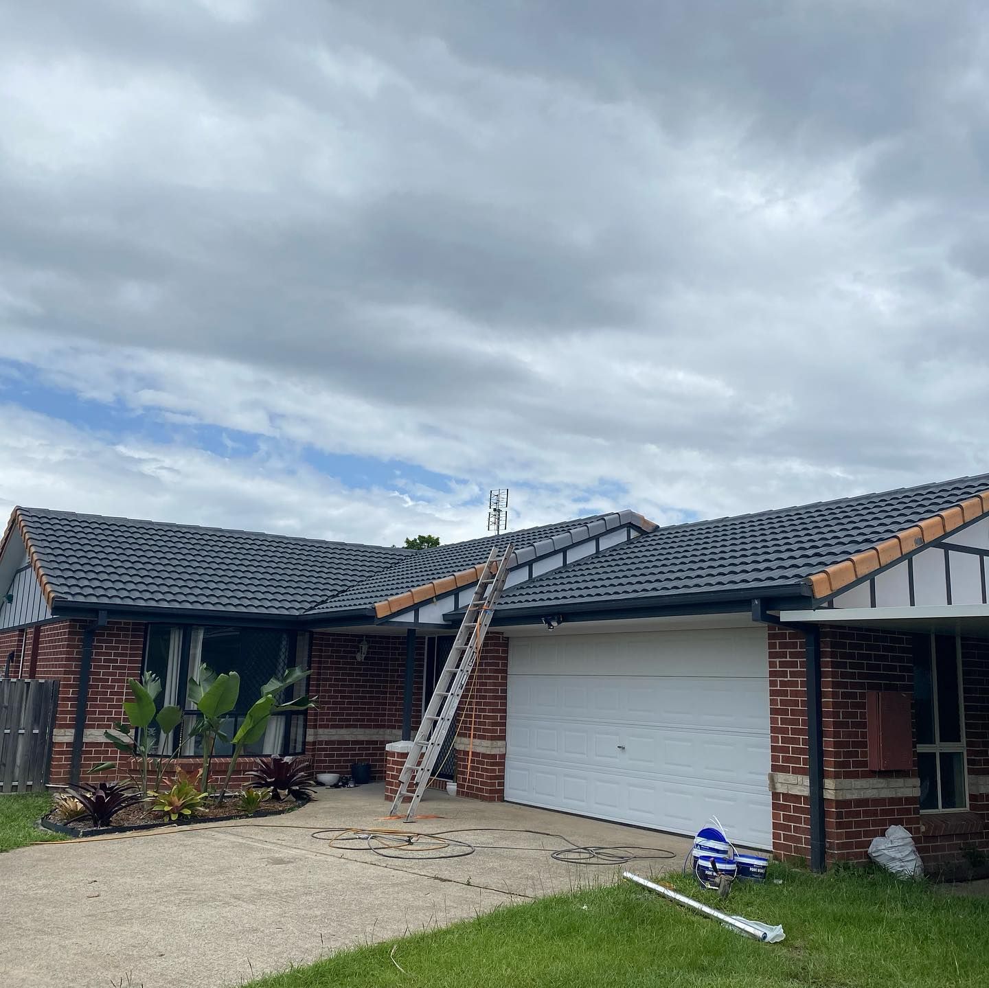 House With Gray Roof, Brick Facade, White Garage Door, Ladder Leaning Against Roof — SEQ Roofing & Painting in Currumbin, QLD