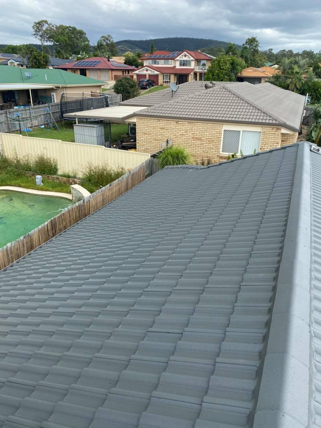 Gray Tiled Roof of a House Overlooking Other Houses in a Suburban Area on a Cloudy Day — SEQ Roofing & Painting in Coomera, QLD