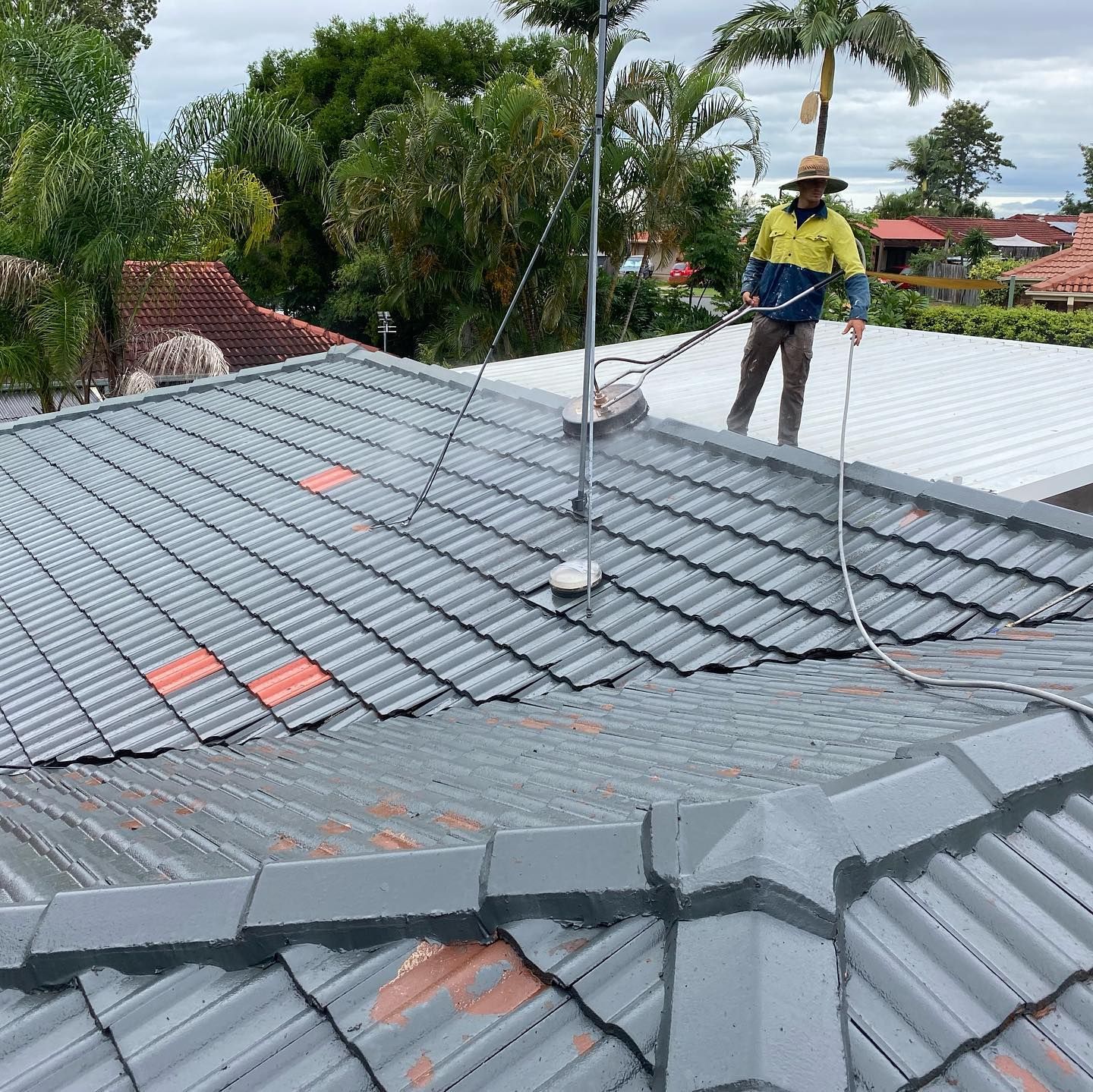 Man Power Washes a Gray Tiled Roof — SEQ Roofing & Painting in Southport, QLD