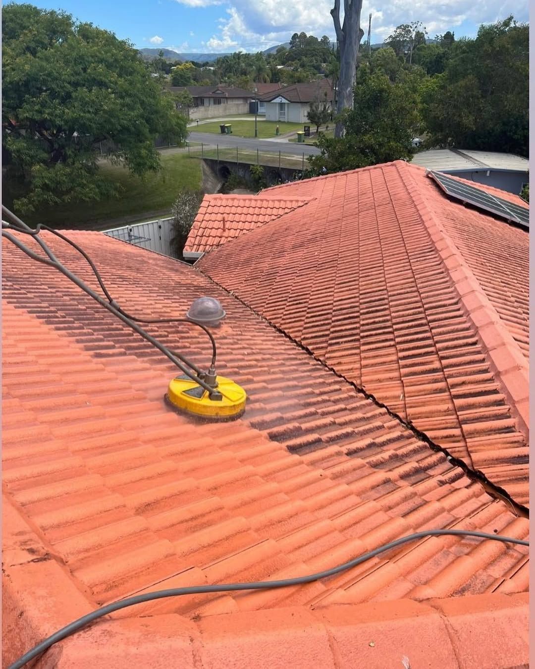a Person Pressure Washing a Terracotta Tile Roof on a Sunny Day — SEQ Roofing & Painting in Mudgeeraba, QLD