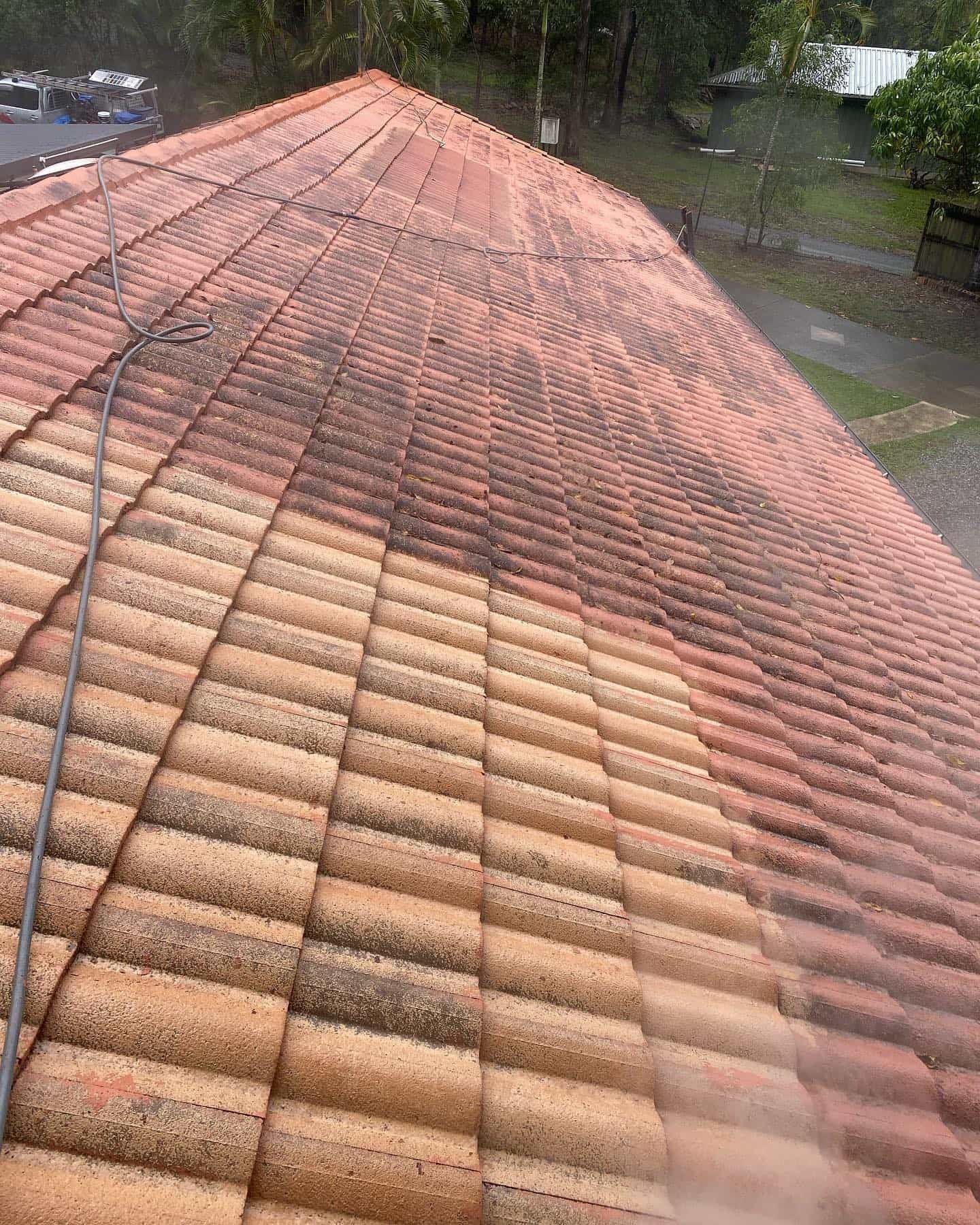 A roof being cleaned with a pressure washer, showing a clear contrast between clean and dirty areas — SEQ Roofing & Painting in Nerang, QLD