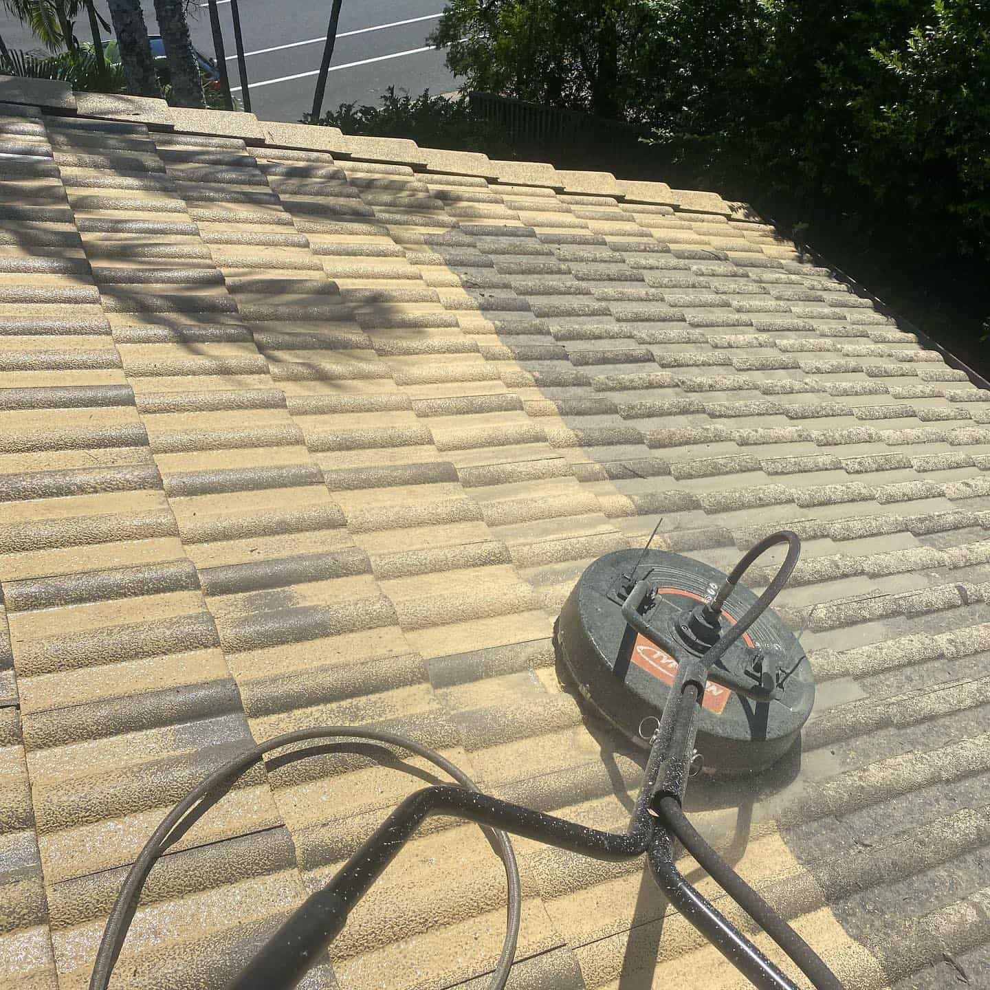 A Person Power Washing a Roof With a Rotating Surface Cleaner, Showing a Strip of Clean Shingles — SEQ Roofing & Painting in Burleigh Heads, QLD