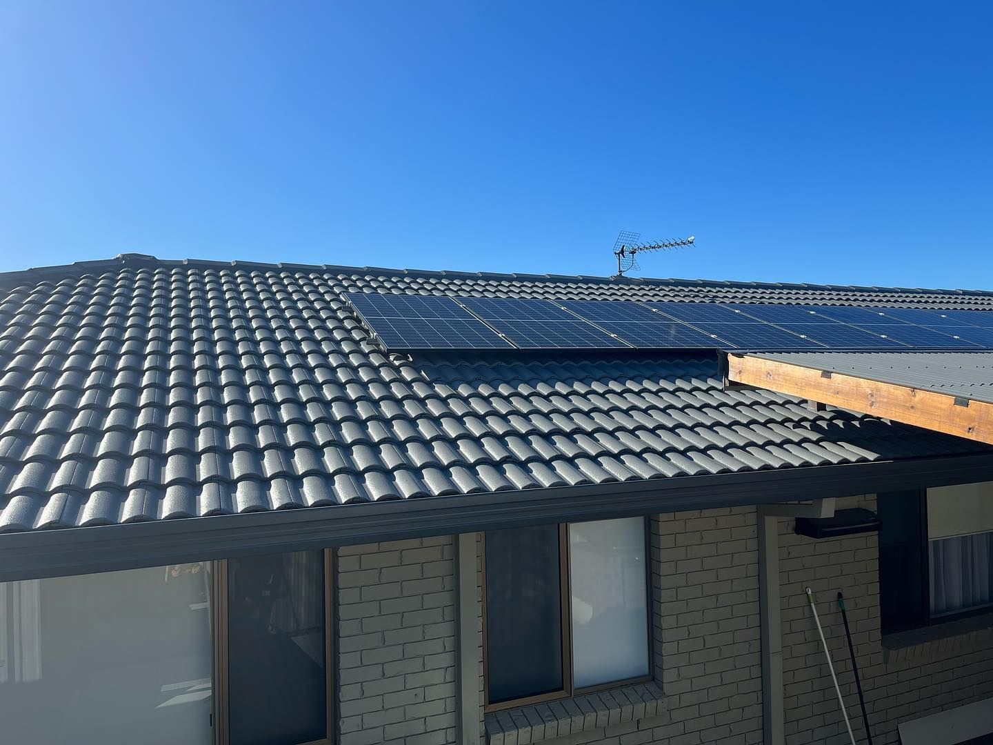 Solar Panels on A Gray Tiled Roof of A Brick Building — SEQ Roofing & Painting in Mudgeeraba, QLD
