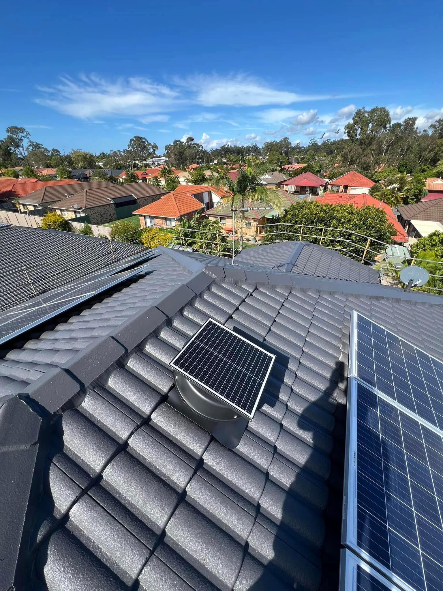 Solar Roof Vent Between Solar Panels on A Tiled Roof, Residential Area Backdrop — SEQ Roofing & Painting in Nerang, QLD