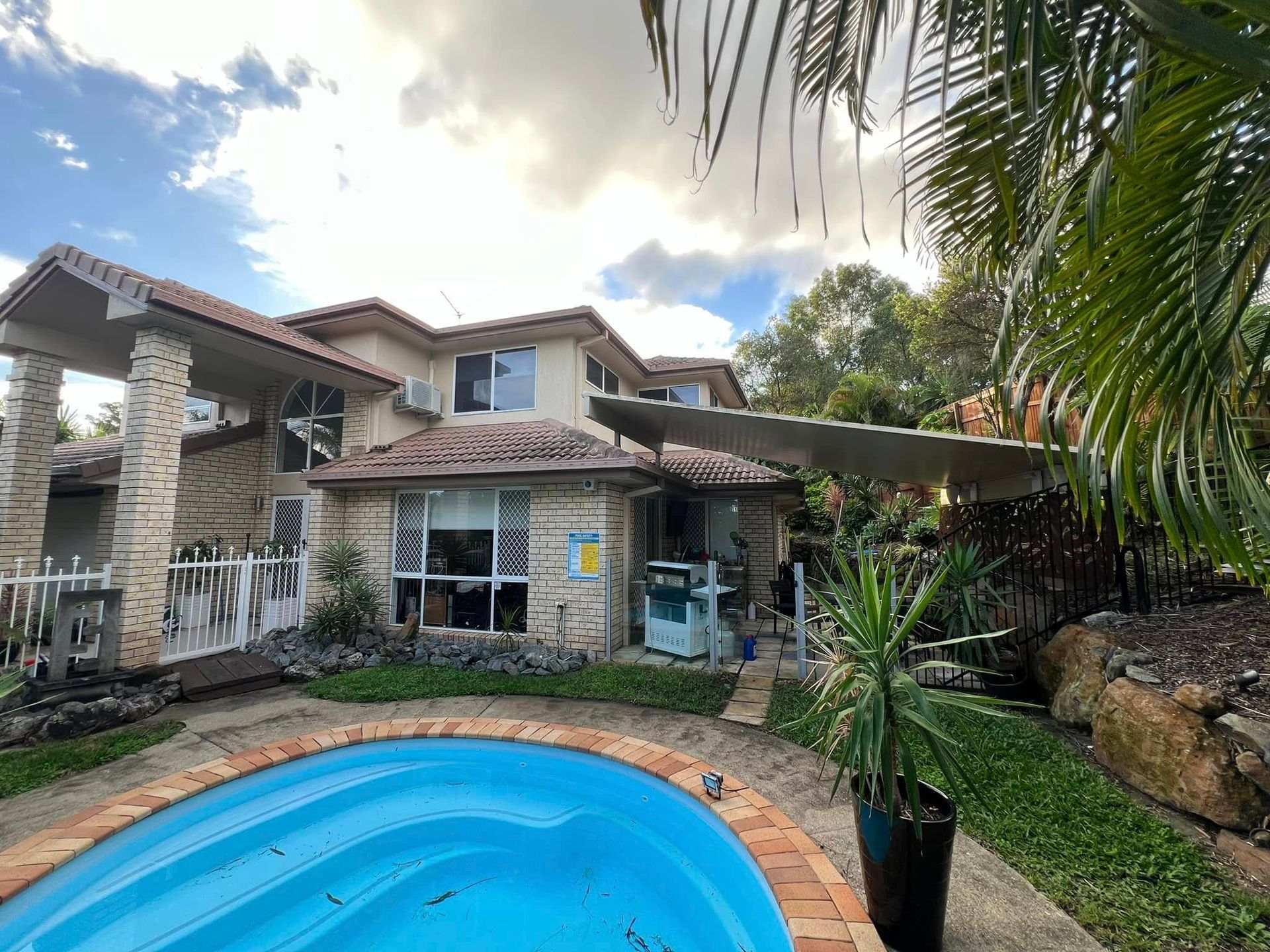 House Exterior With a Pool, Palm Trees, and Overcast Sky — SEQ Roofing & Painting in Currumbin, QLD