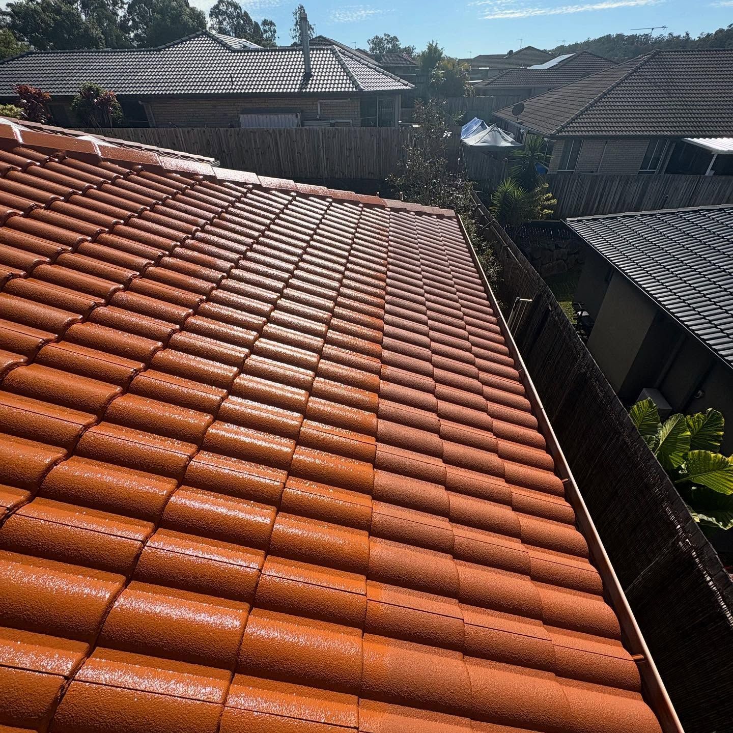 Orange Tiled Roof, with Gutter in Foreground and Suburban Houses — SEQ Roofing & Painting in Nerang, QLD