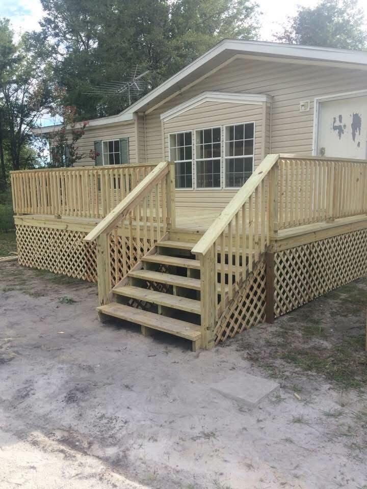 Wooden ramp and stairs leading to a beige house with lattice skirting and a porch railing