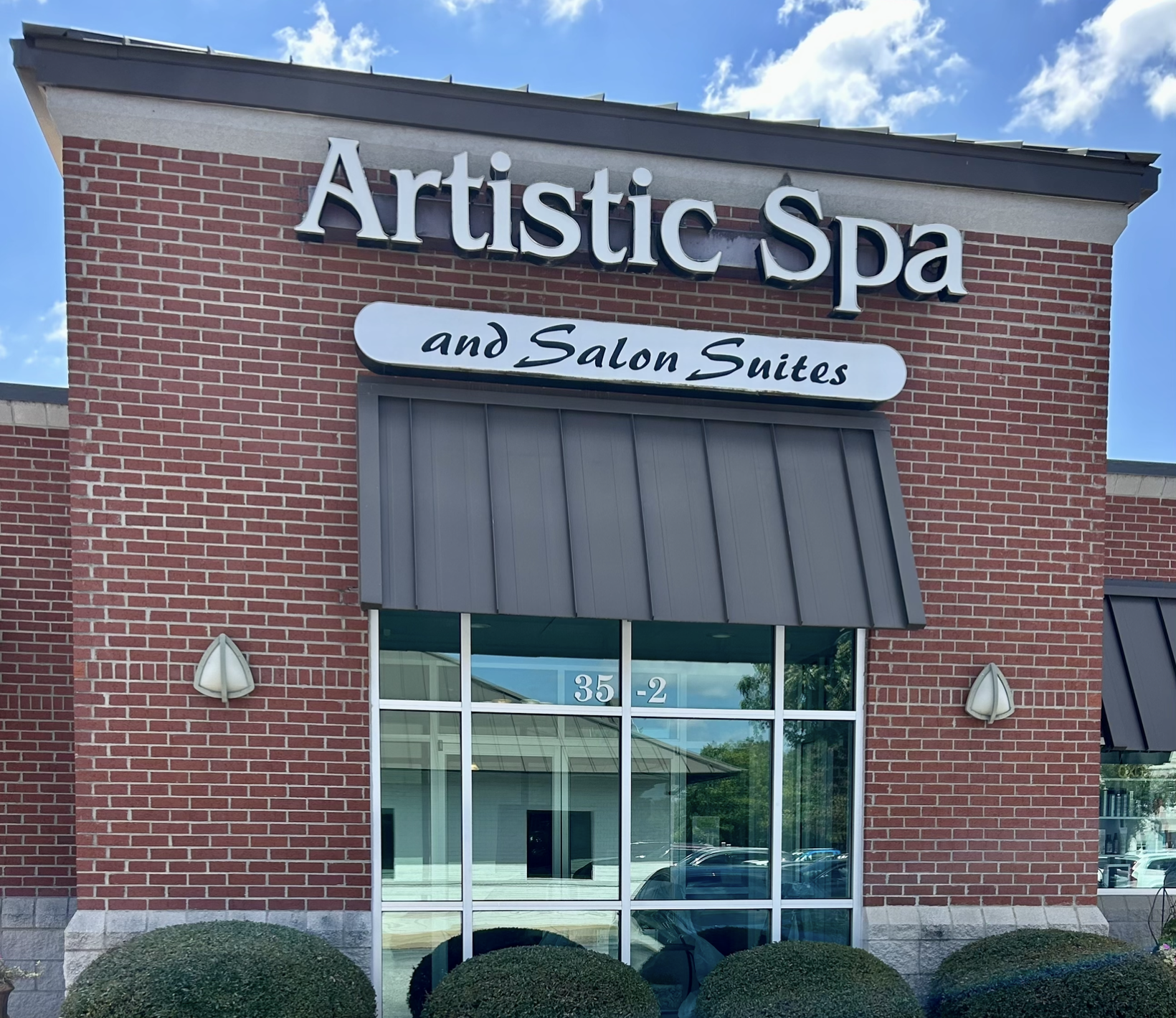 Salon interior with a shampoo station, shelves of products, artwork, and decorative items.