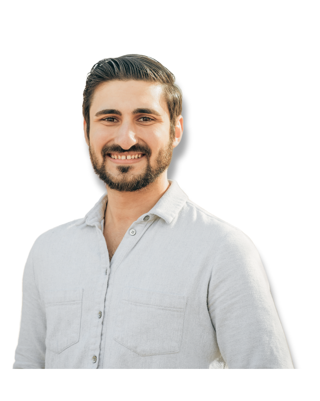 Man with a beard smiling, wearing a light button-down shirt, outdoors.