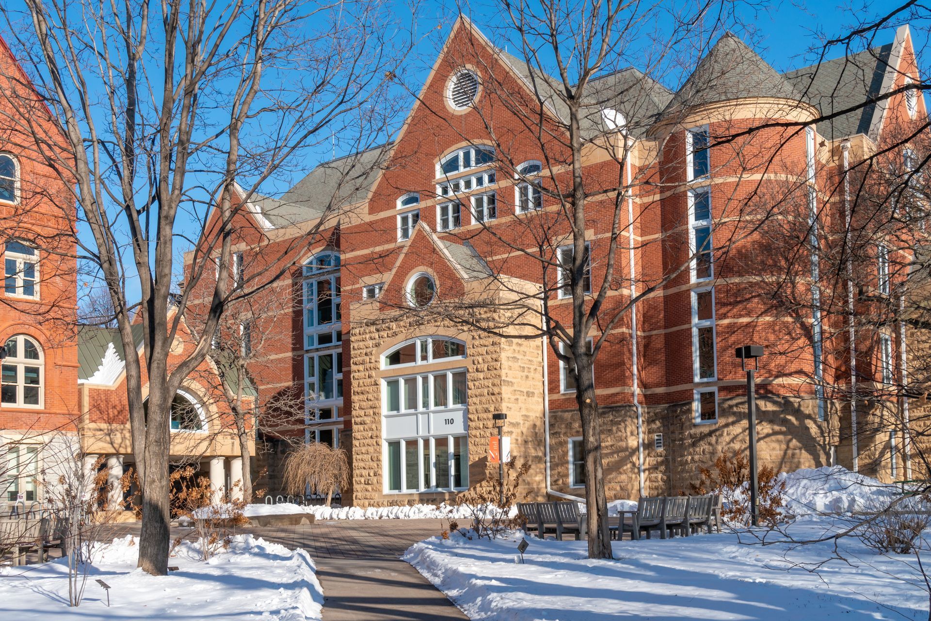 A large brick building with snow on the ground in front of it.