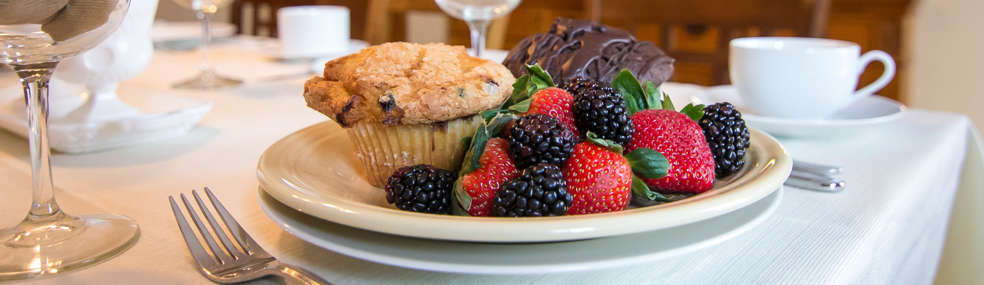 A plate of berries and a muffin on a table.
