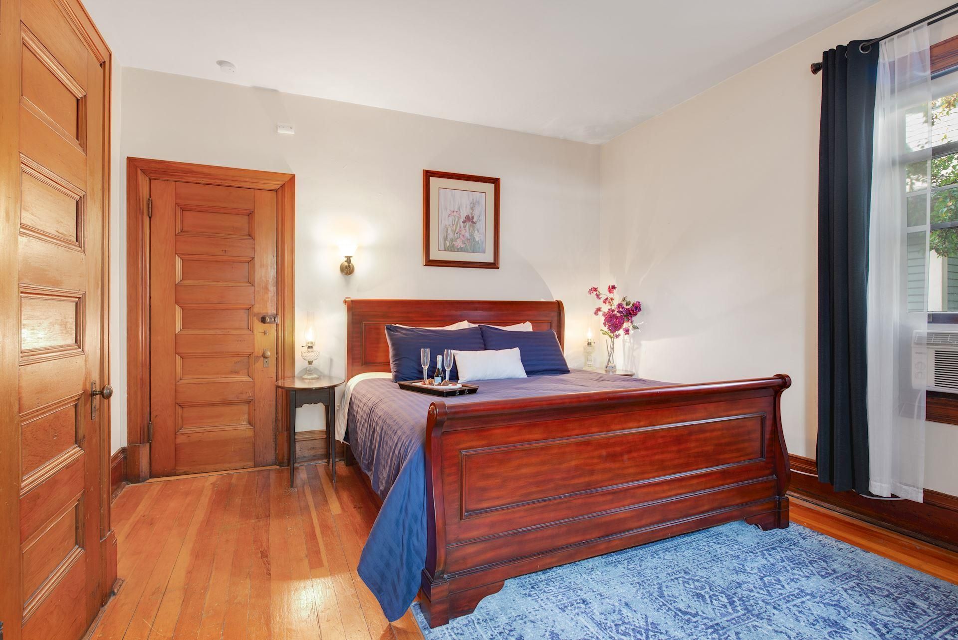 A bedroom with a wooden bed and a blue rug.