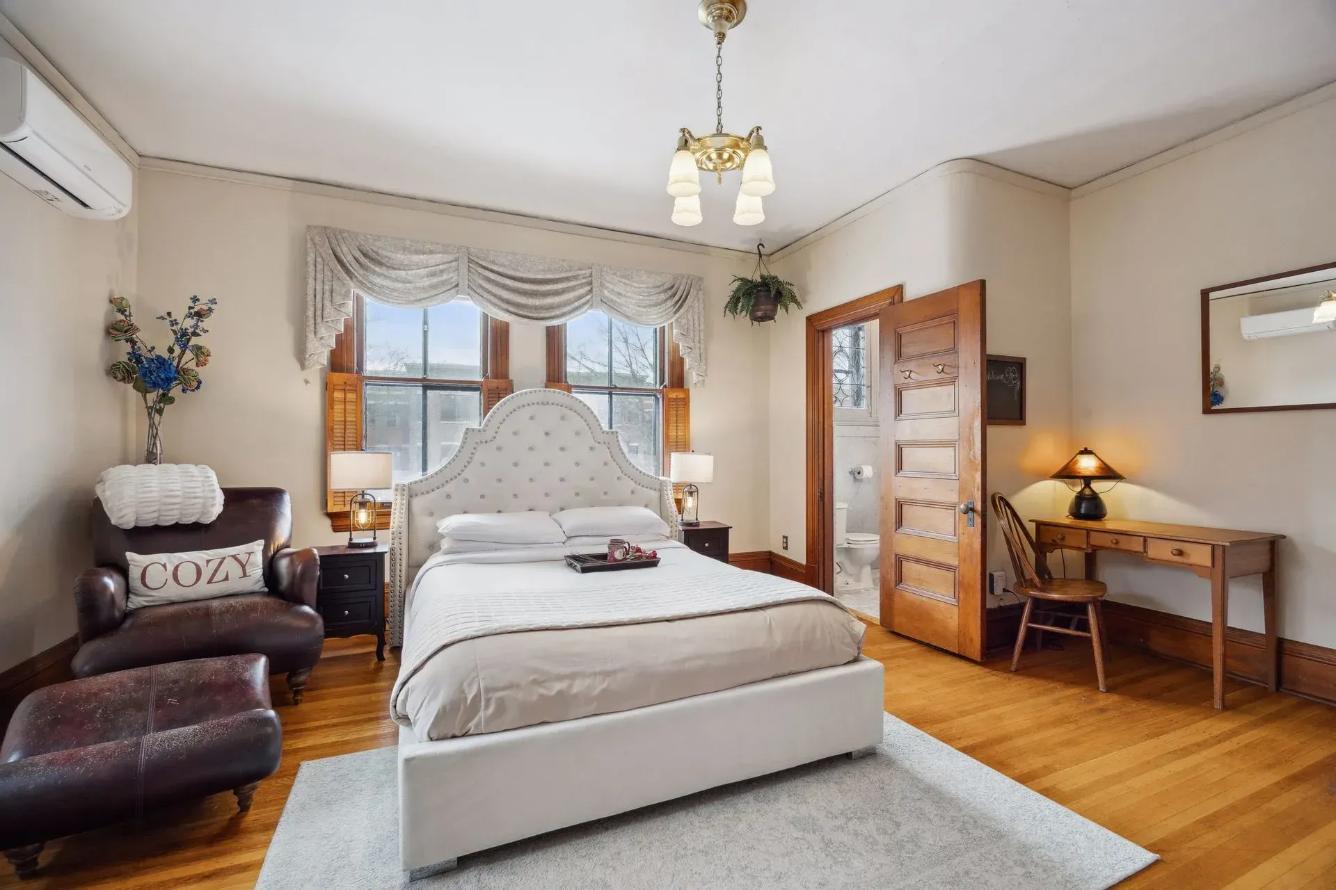 A bedroom with a large bed , chairs , desk and mirror.