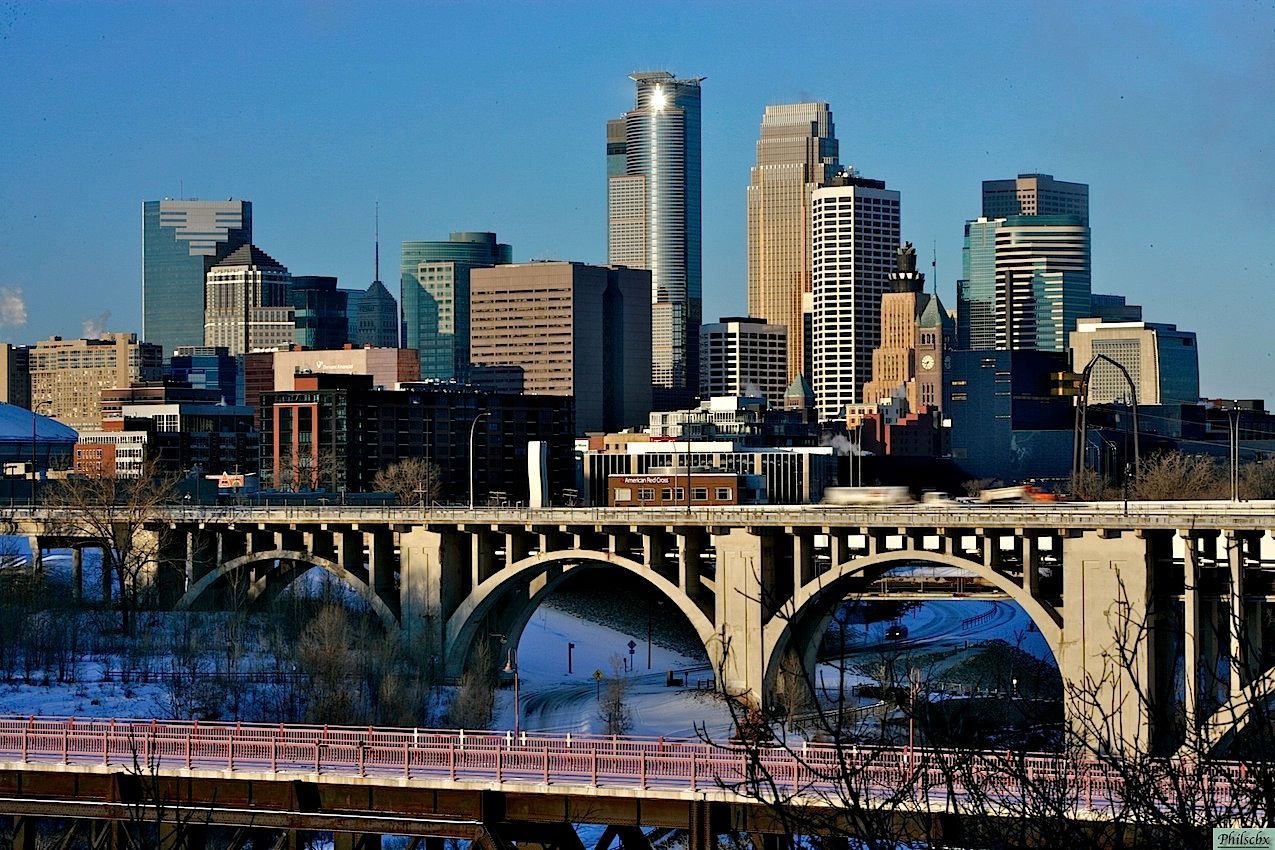 A bridge over a river with a city skyline in the background