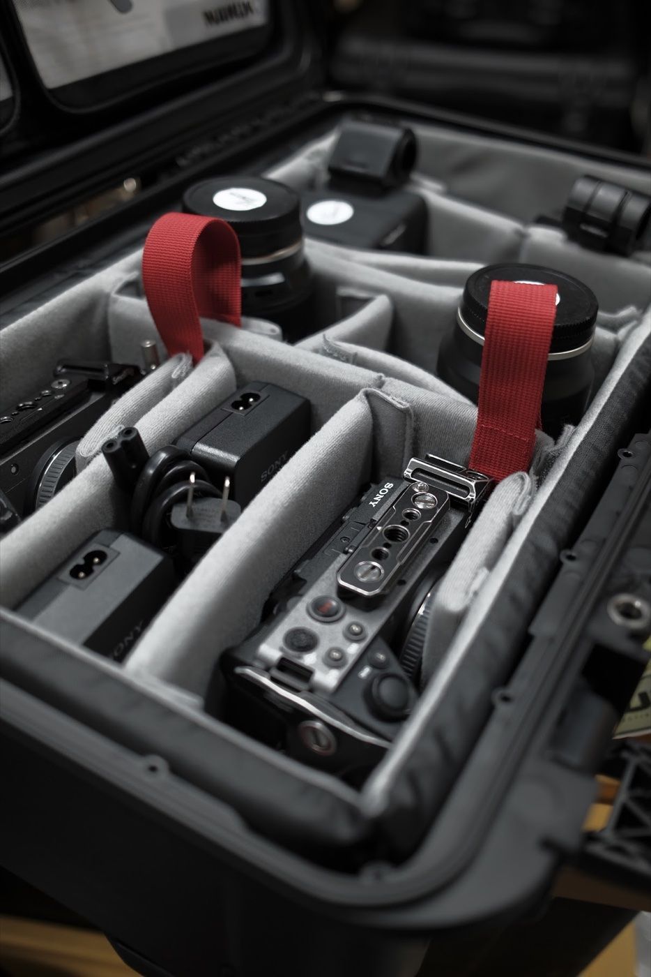 Camera, lenses, chargers and power accessories arranged in a padded equipment case.