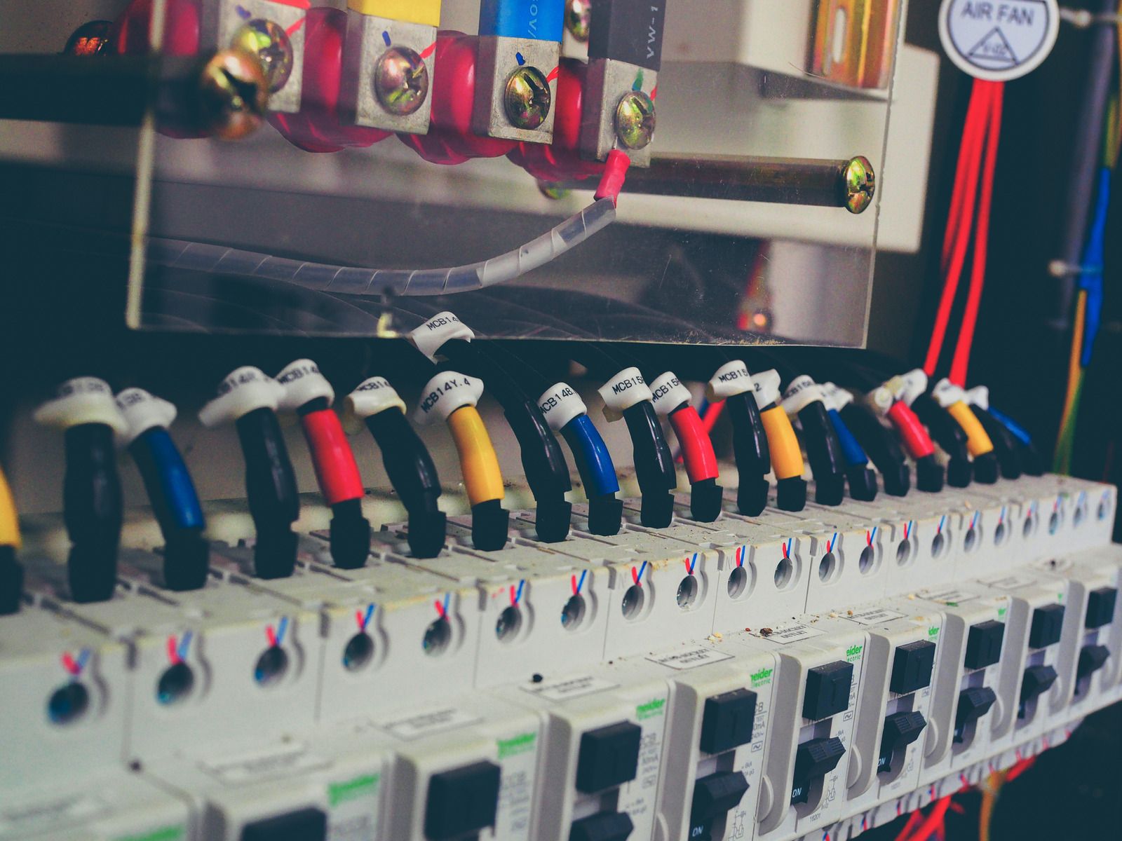 Electrical panel with colored wires connected to circuit breakers.