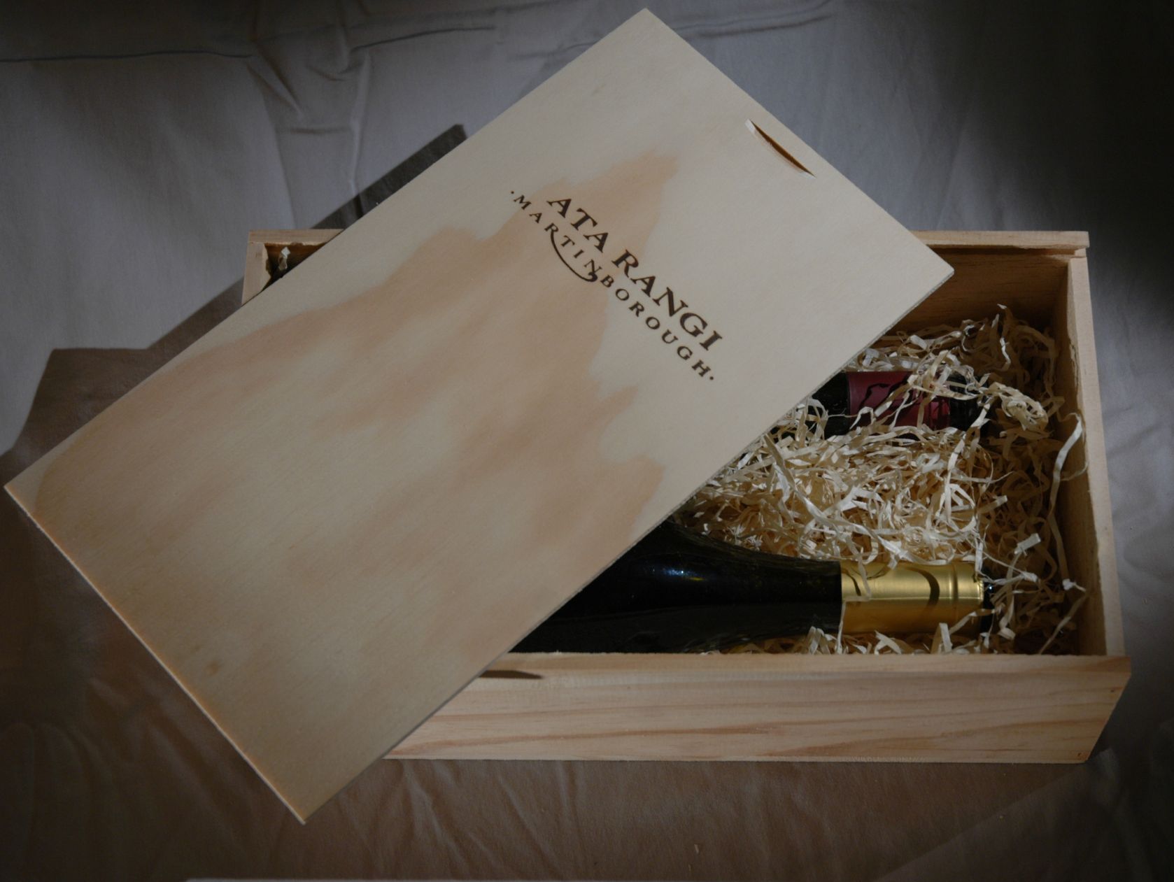 A wooden box filled with wine bottles and glasses on a wooden floor.