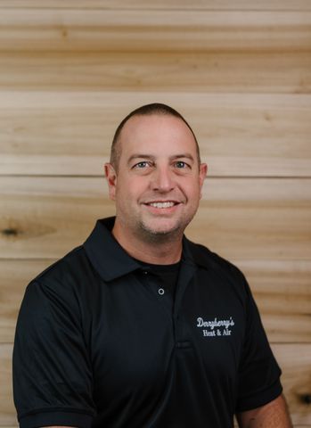 Man in black polo shirt smiles in front of wood background. Text 