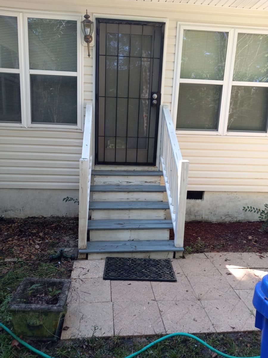 A white house with stairs leading up to the front door.